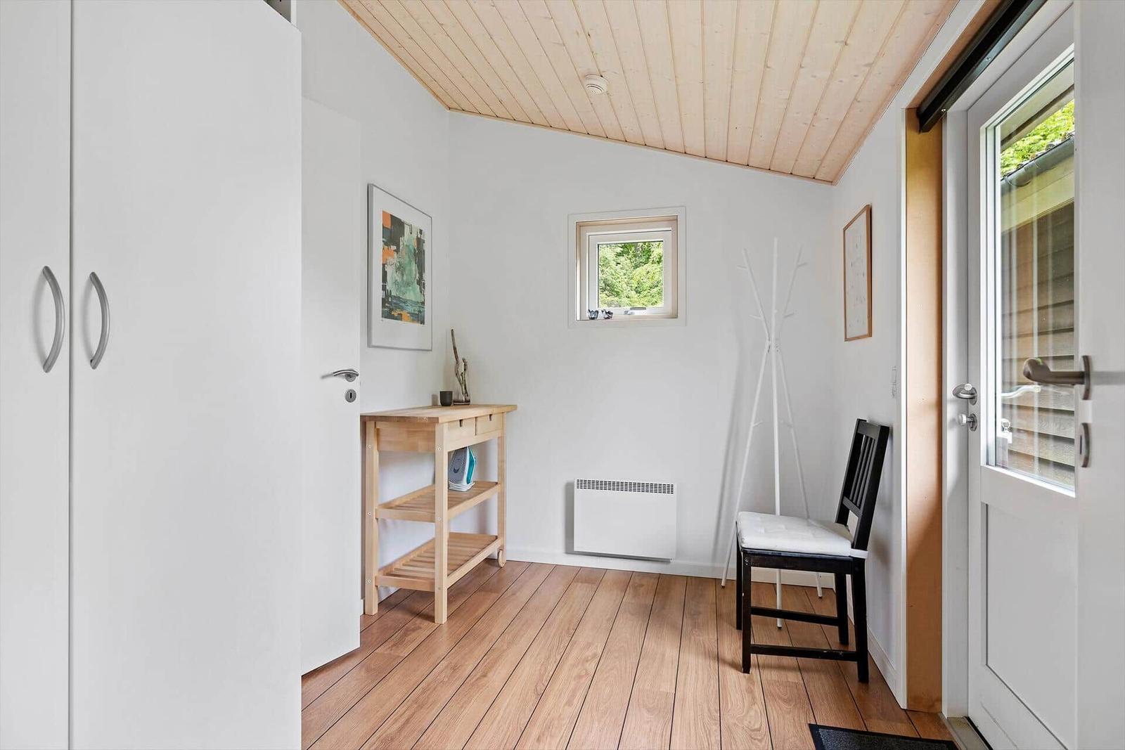 Eingangsbereich mit Holzboden, Kleiderständer und Tür zum Außenbereich.