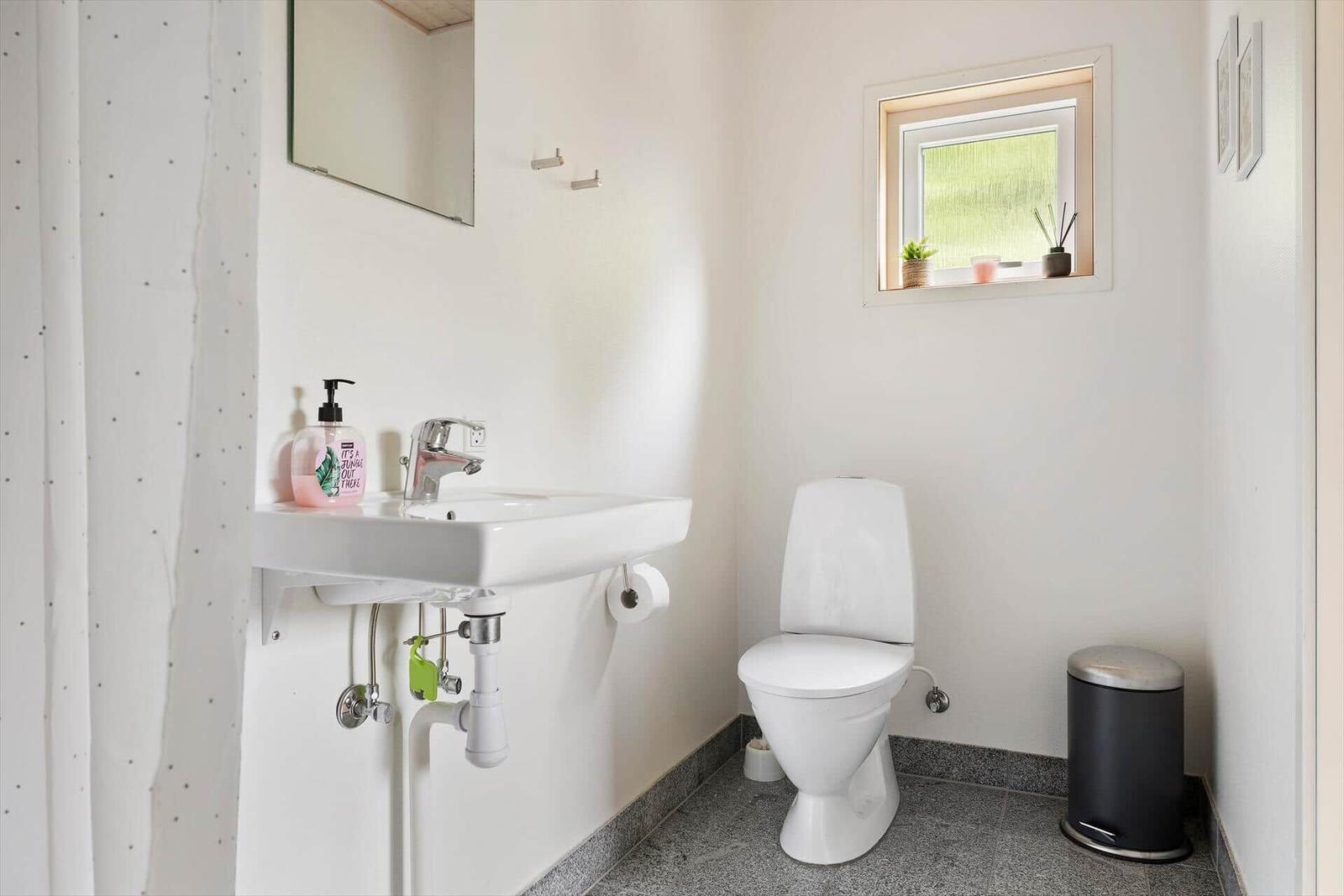 Badezimmer mit Waschbecken, Toilette und kleinem Fenster.