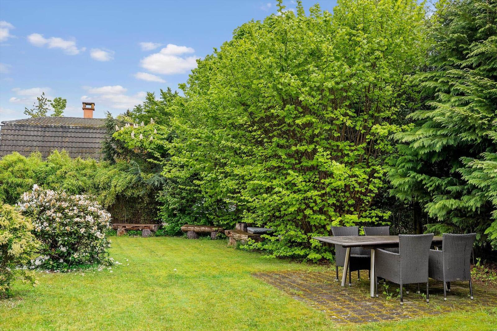 Garten mit Sitzgruppe, Bäumen und Grasfläche. Hintergrund: Haus mit Schieferdach.