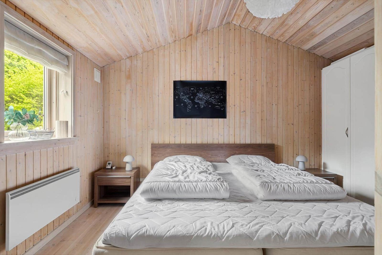 Schlafzimmer mit Holzwand, Bett, Nachttisch und Fenster
