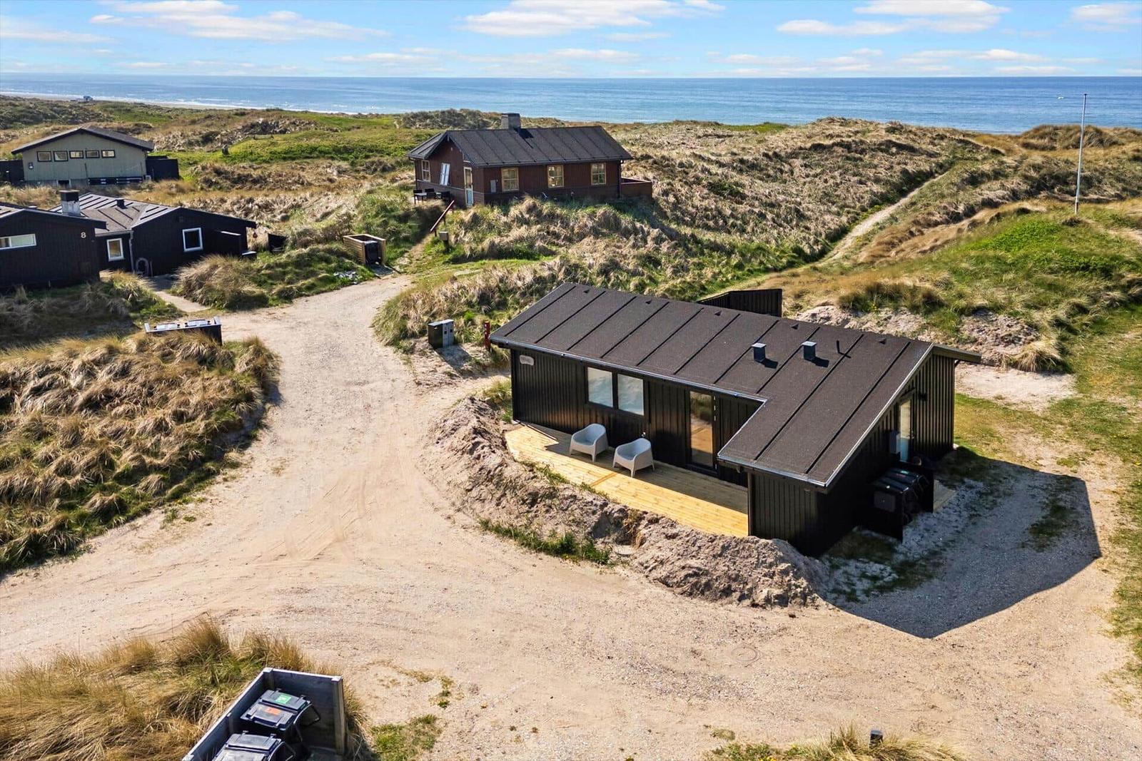 Modernes Strandhaus mit Terrasse und Meerblick zwischen Dünen.