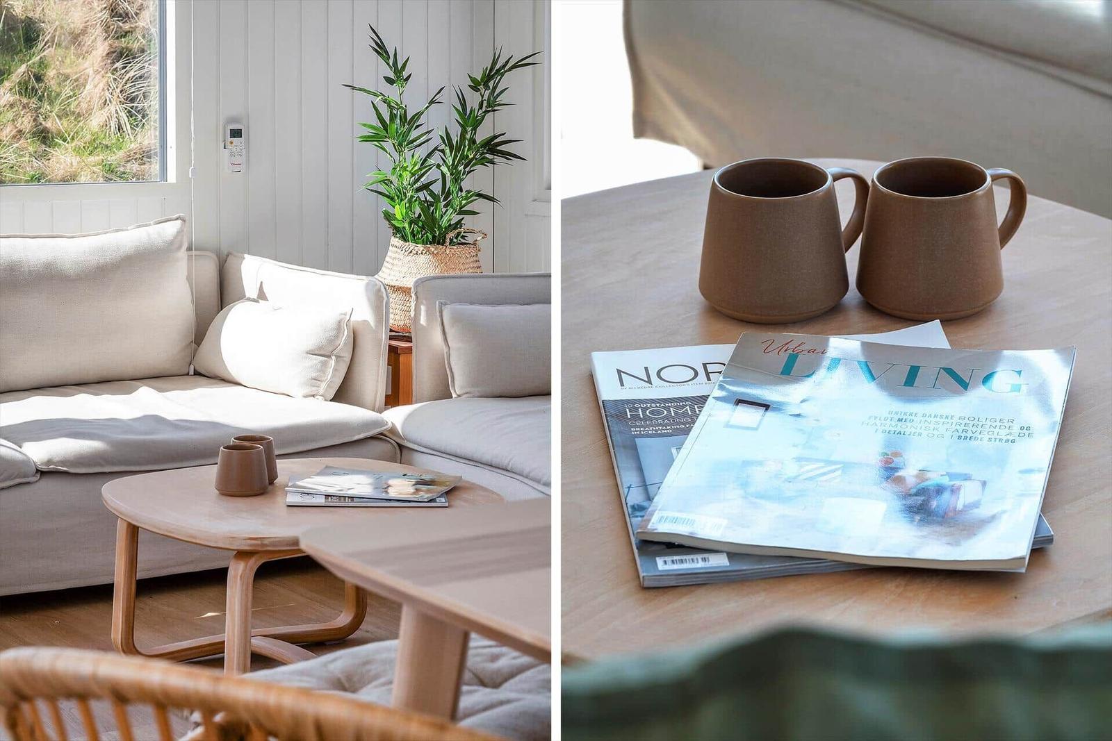 Wohnzimmer mit Sofa, Tisch und Pflanze. Tisch mit Tassen und Magazinen.