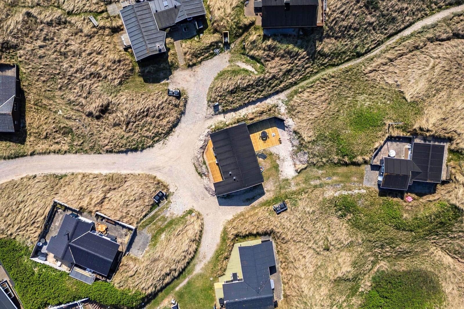 Luftbild von mehreren Häusern mit Dächern und Terrassen in einer grasbewachsenen Landschaft.