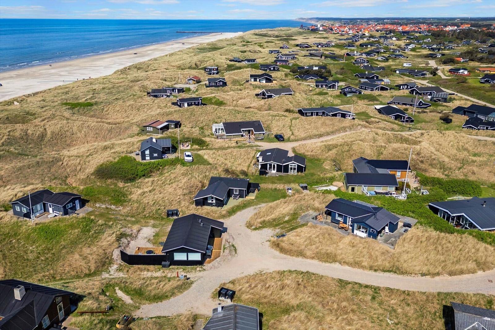 Aeriale Aufnahme von Strandhäusern auf Dünen mit Blick auf das Meer.