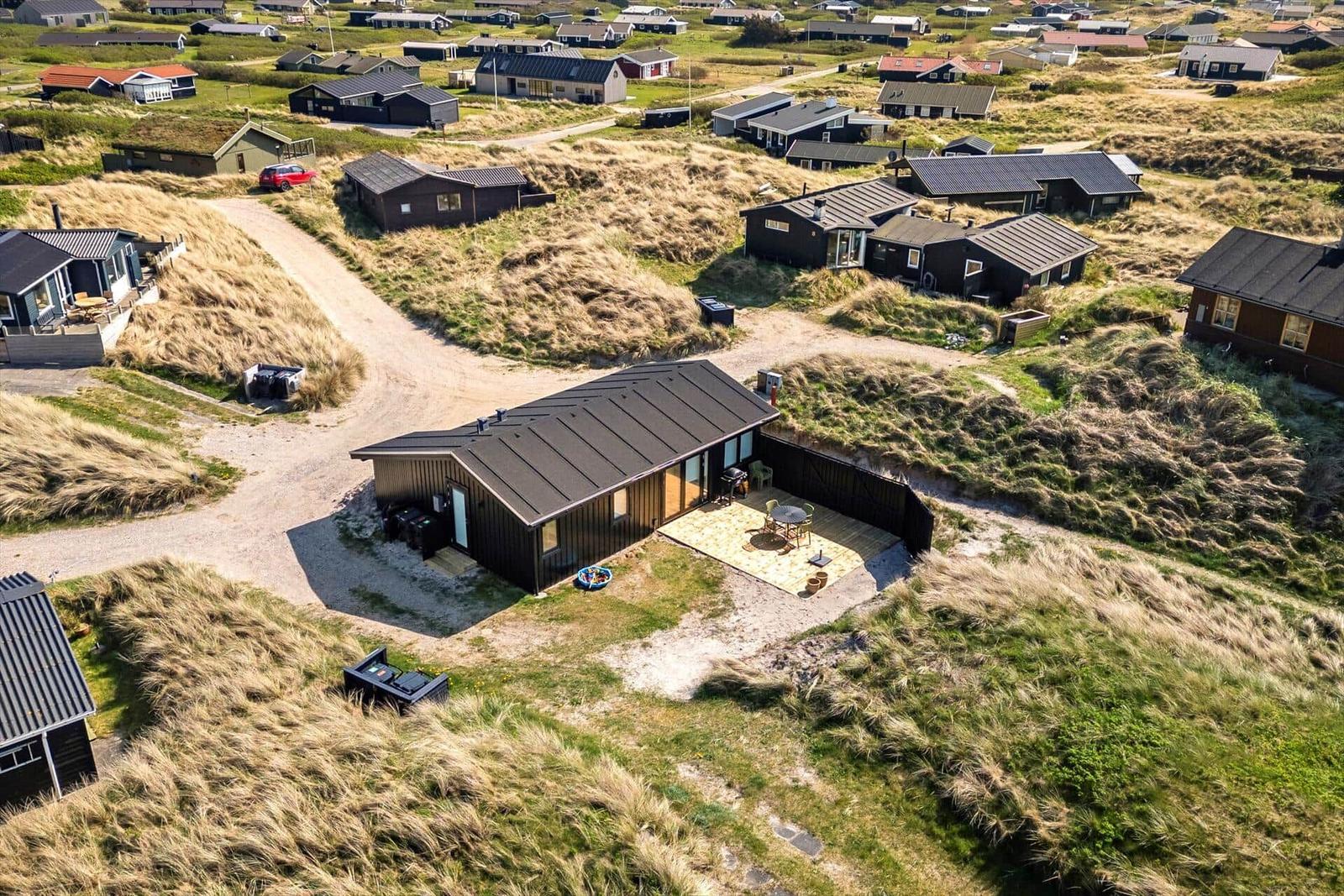 Moderne Strandhütte mit Terrasse zwischen Dünen und Häusern