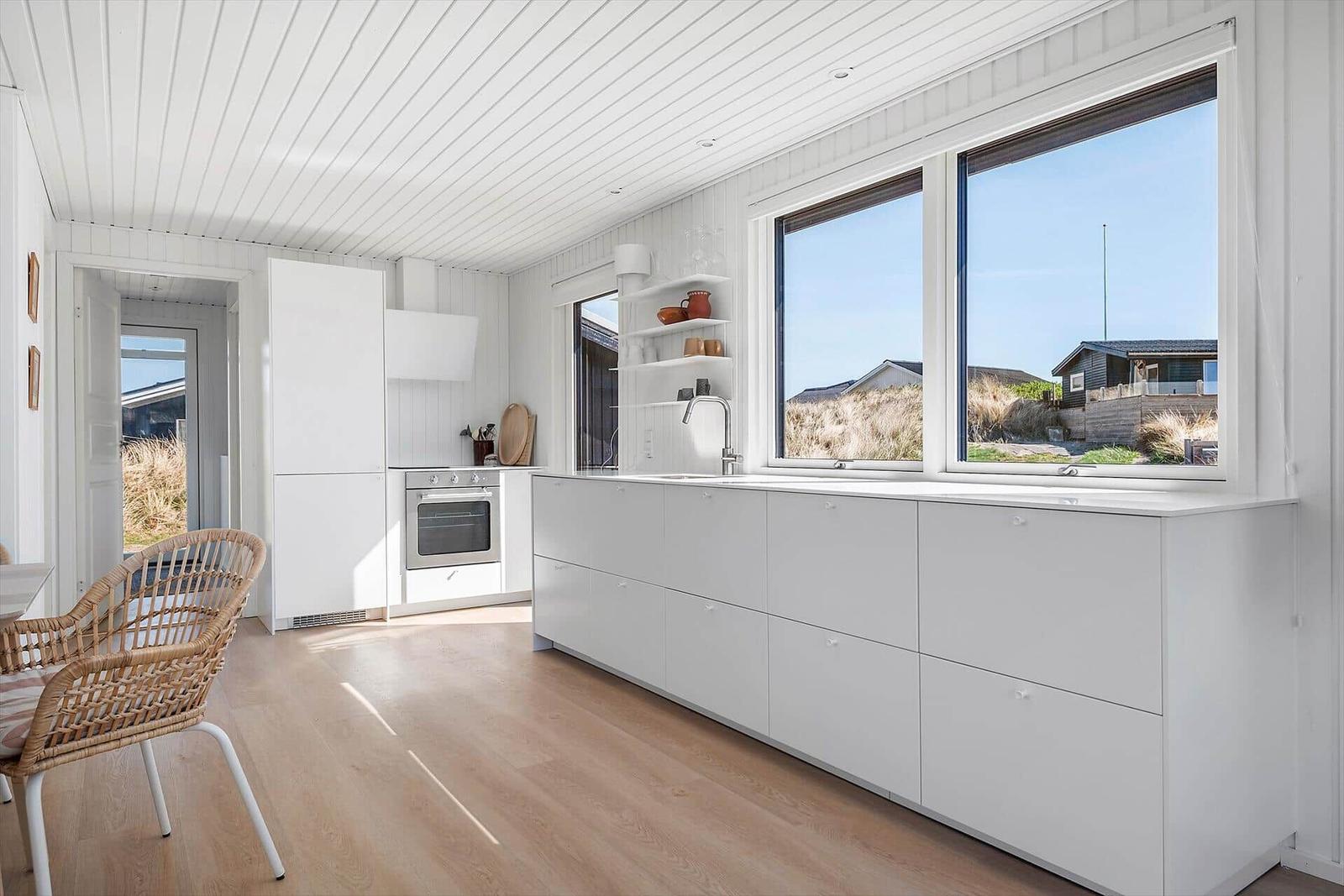 Küche mit weißen Schränken und großem Fensterblick