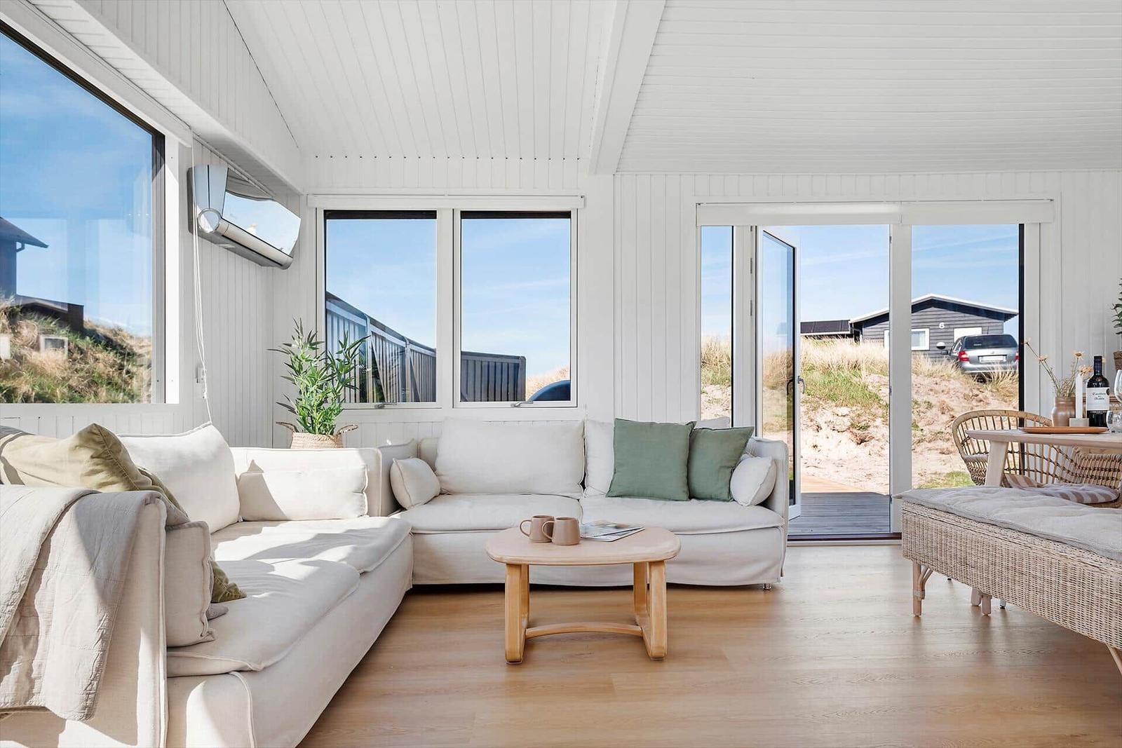 Wohnzimmer mit Sofa, Tisch und Blick auf die Dünen.
