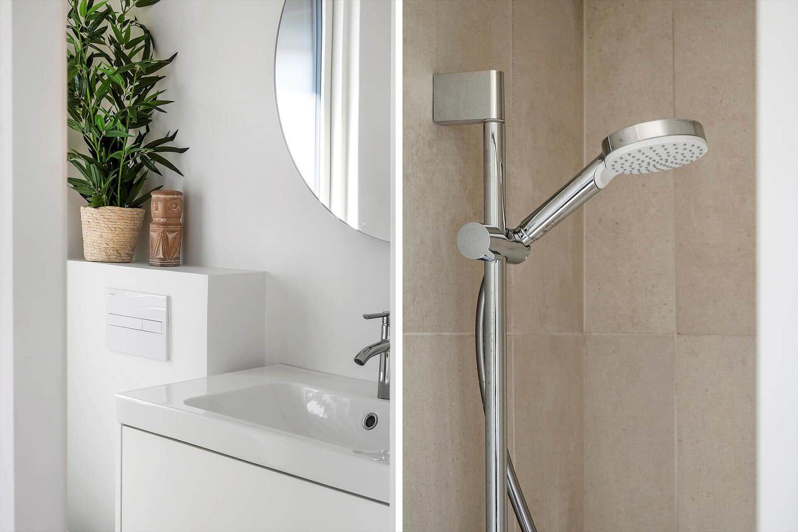 Bad mit Waschbecken, Spiegel und Dusche mit Handbrause.