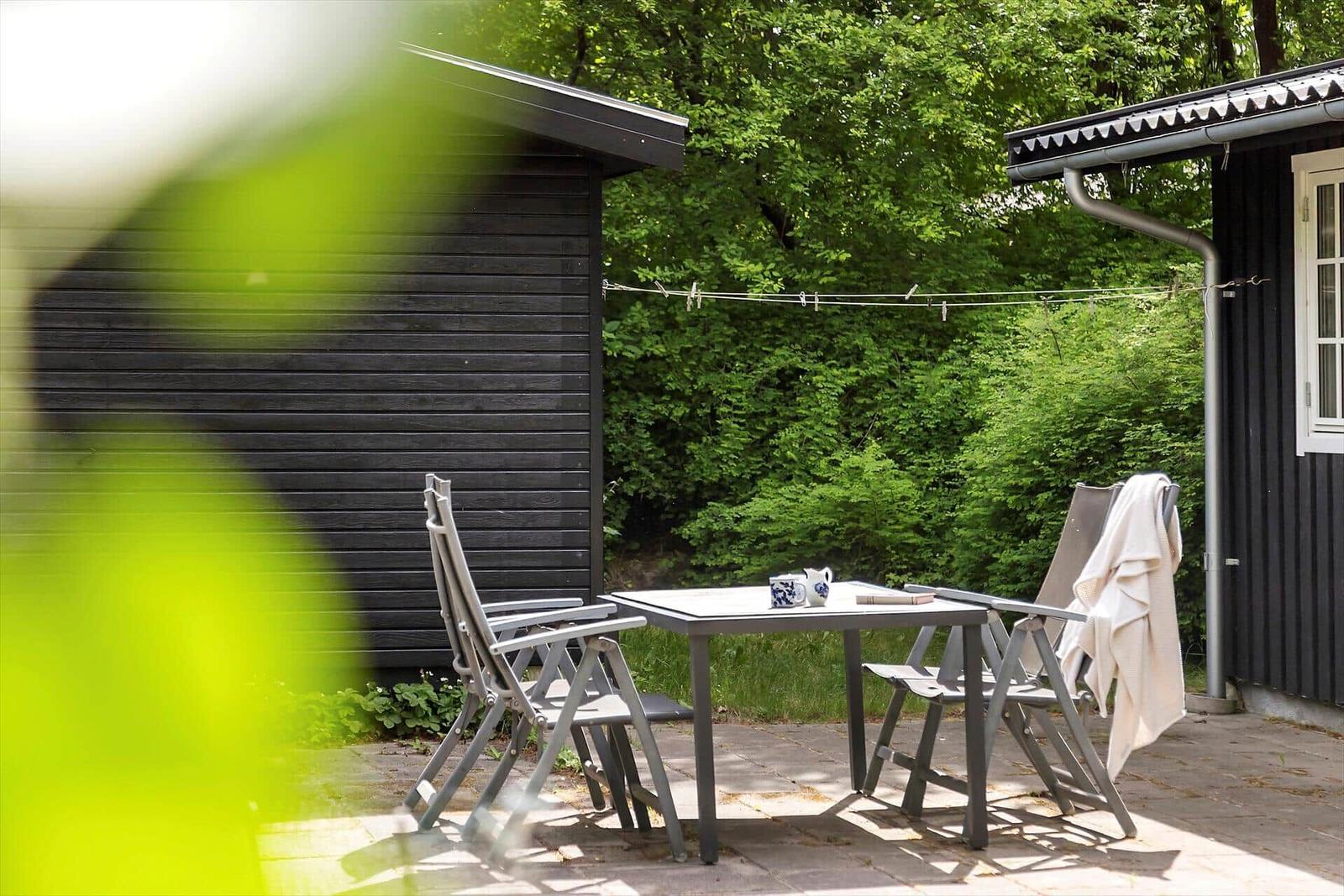 Outdoor patio with table and chairs in front of black wooden house
