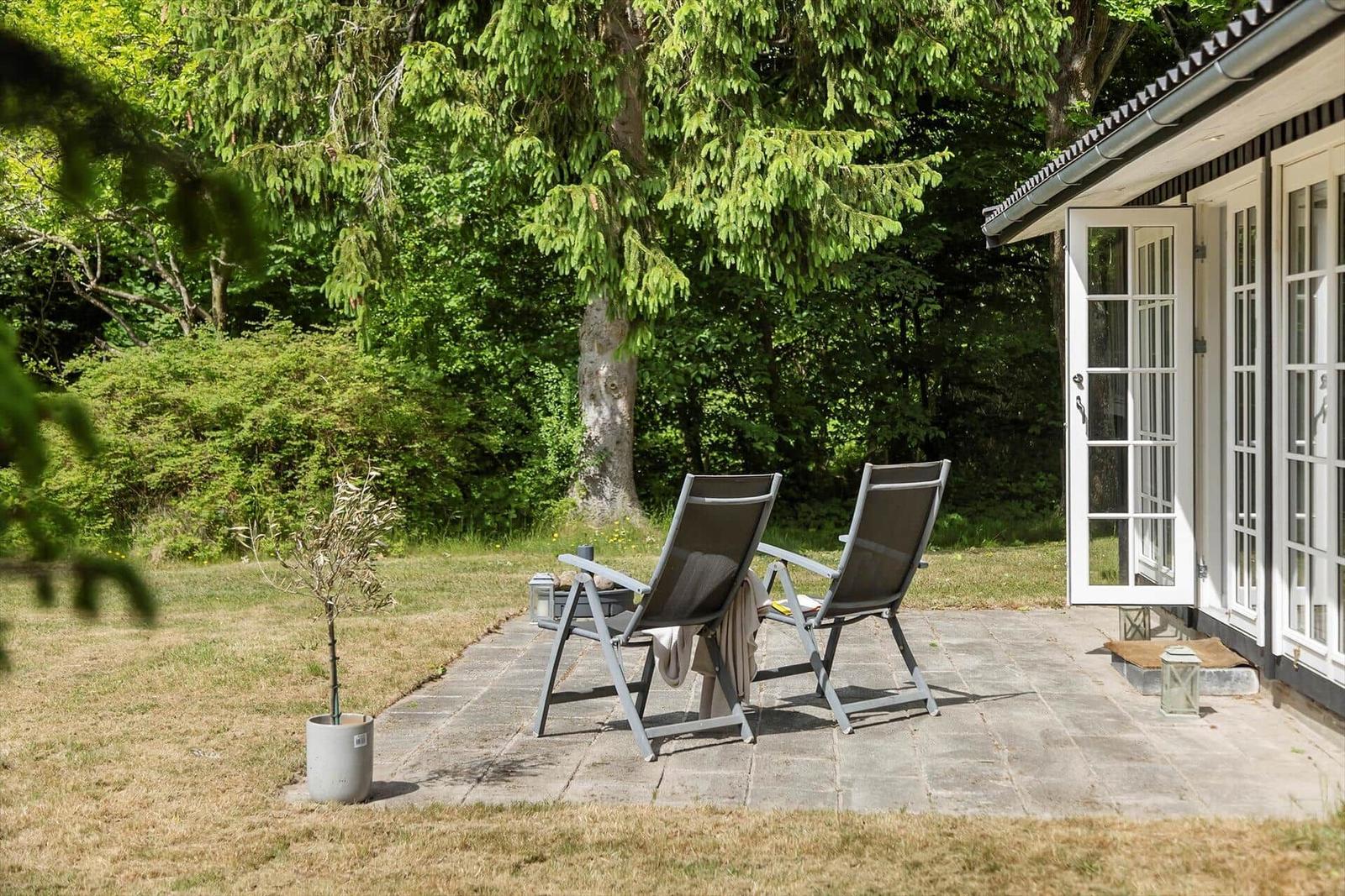 Terrace with two lounge chairs and view of green trees.
