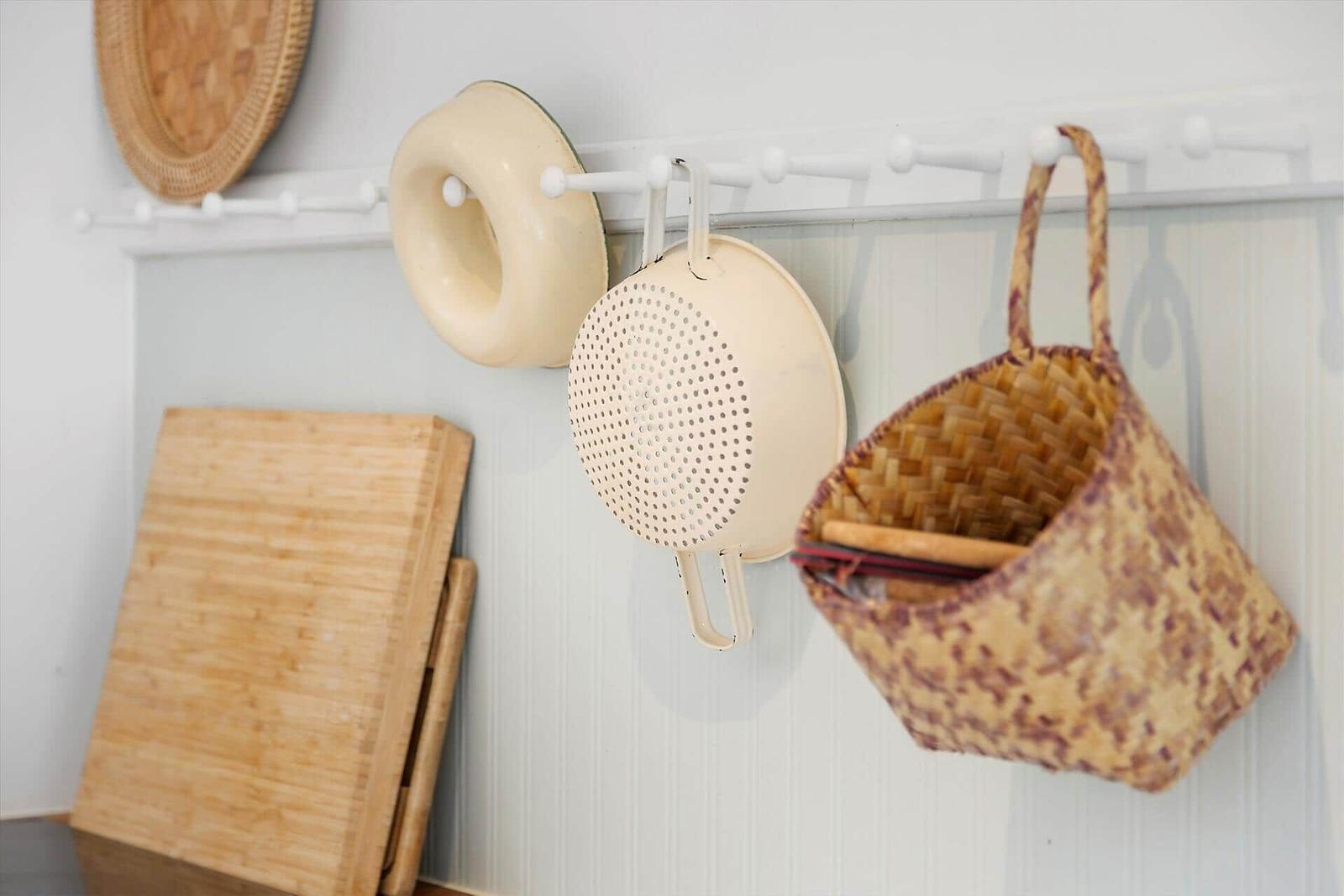 Kitchen wall with hooks holding a colander, a bowl, and a basket.
