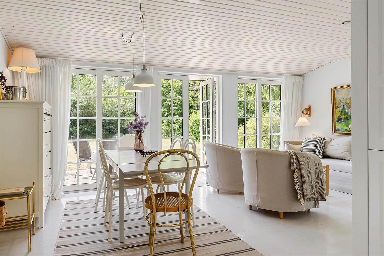 Dining area with table and chairs, living area with sofa and windows to the garden.
