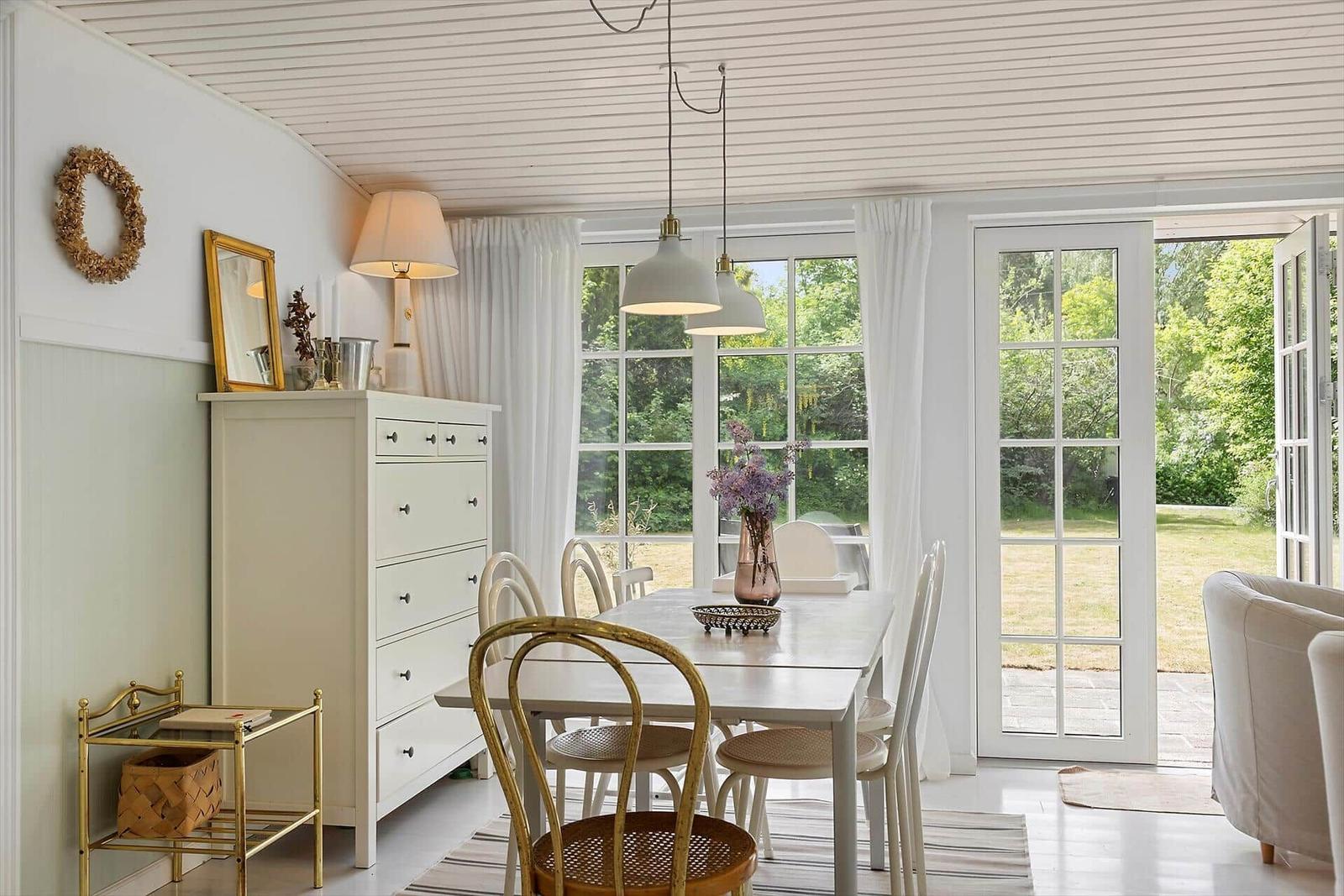 Dining room with table, chairs, and windows to the garden.