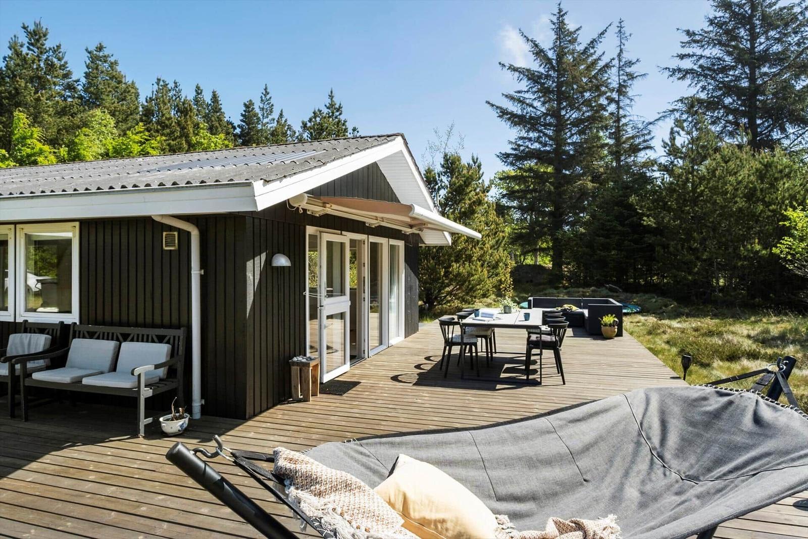 Holzterrasse mit Sitzgelegenheiten und Blick in den Wald.