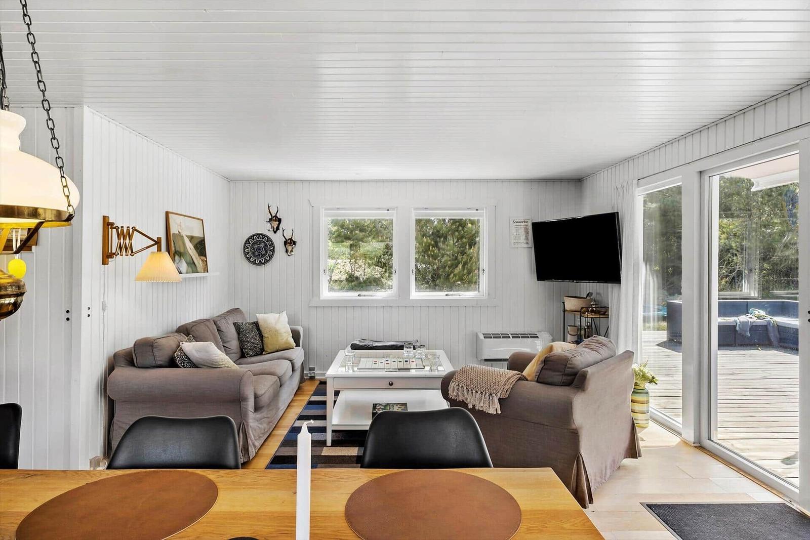 Wohnzimmer mit Sofa, Couch und TV. Durchgang zur Terrasse mit Blick auf den Pool.