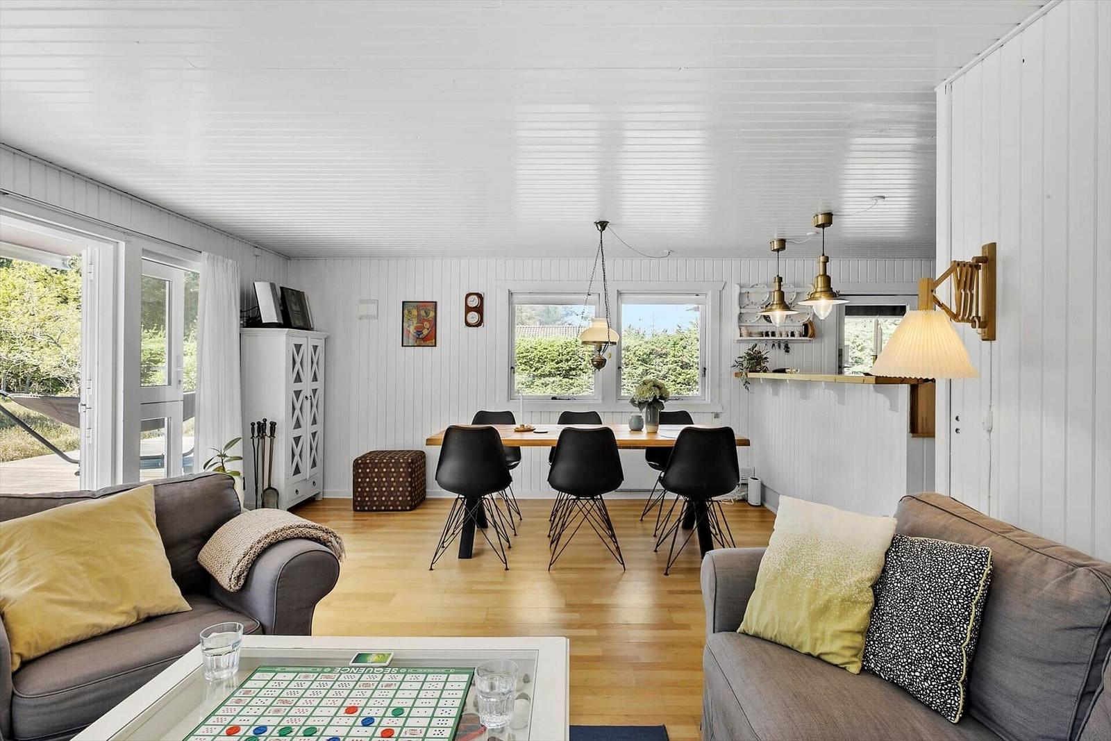 Wohn- und Essbereich mit Sofa, Tisch und Stühlen. Holzboden und weiße Wände.