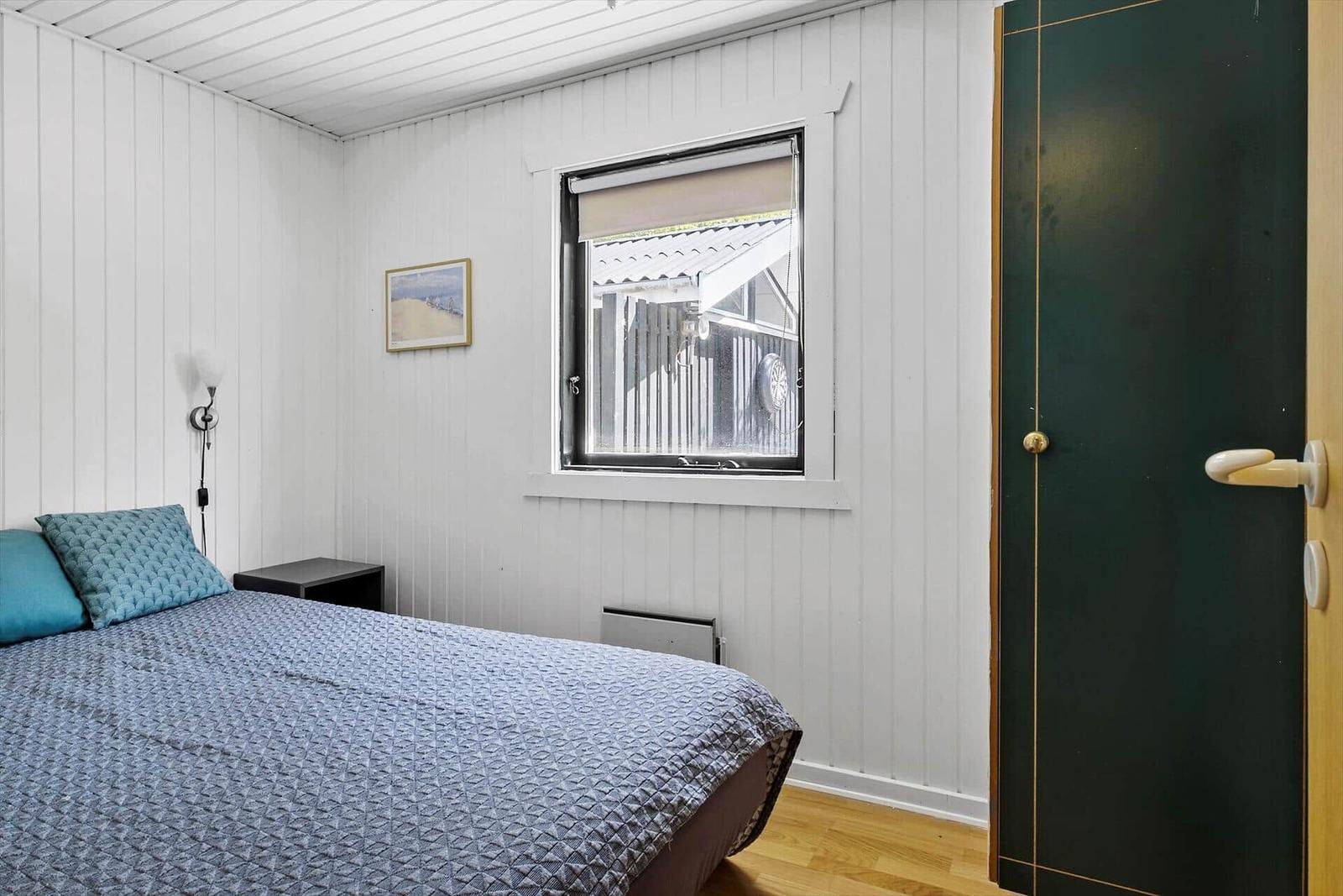 Schlafzimmer mit Bett, Fenster und grüner Tür.