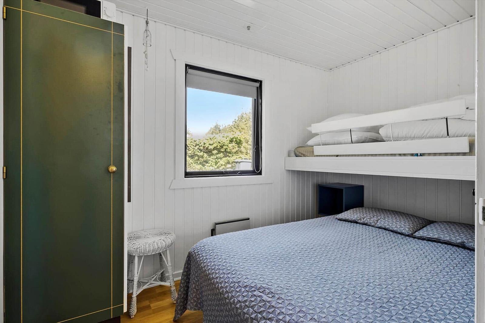 Zimmer mit Doppelbett, Schlafcouch und Fenster mit Blick auf Bäume.