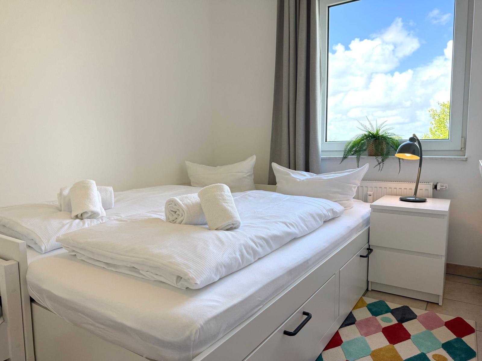 Schlafzimmer mit Doppelbett, Nachttisch und Fenster mit Blick.