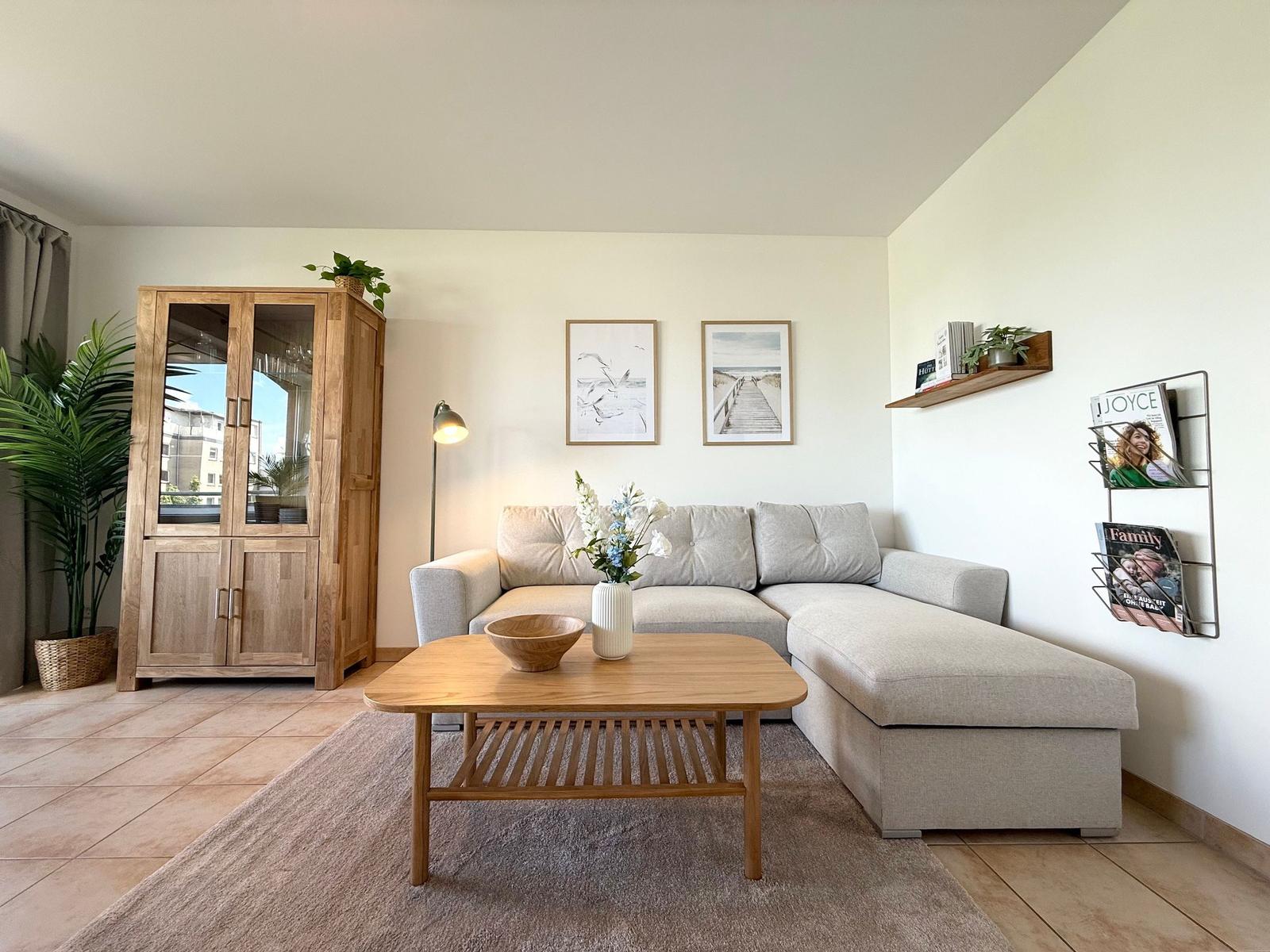 Wohnzimmer mit Ecksofa, Holztisch und Glaswand-Schrank.