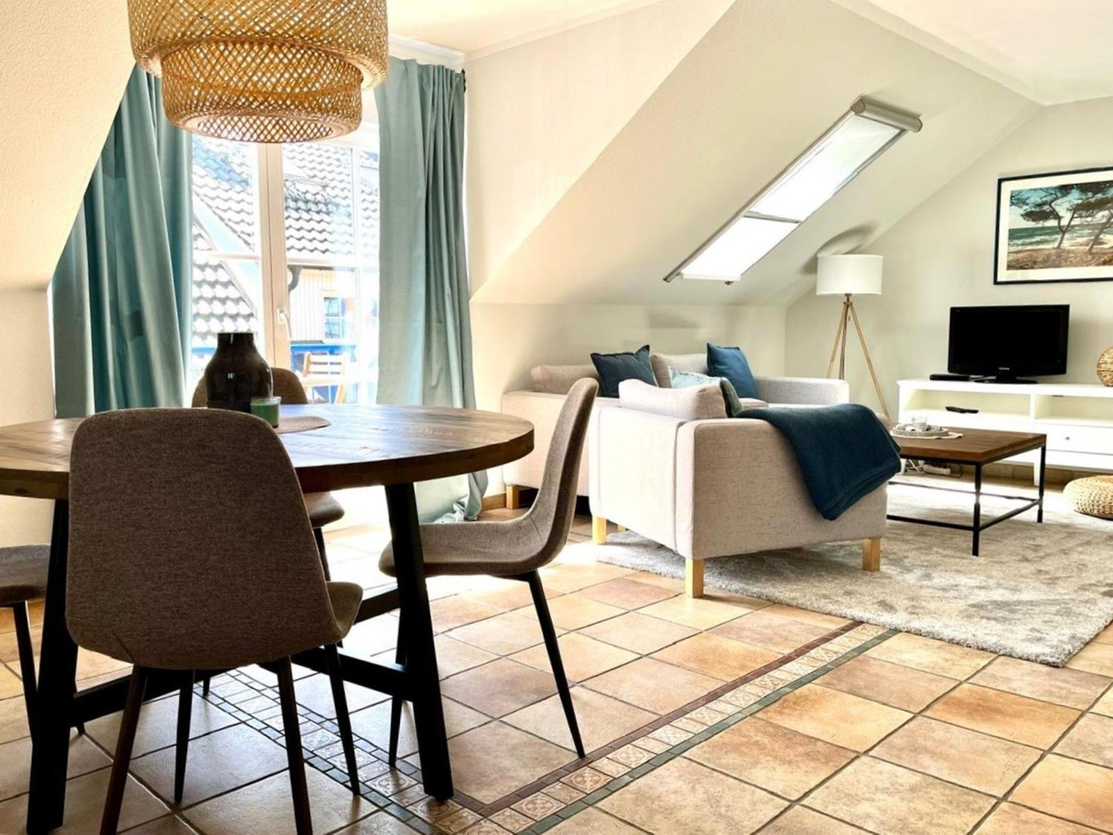 Wohn- und Essbereich mit Sofa, Tisch und TV unter Dachschrägen.