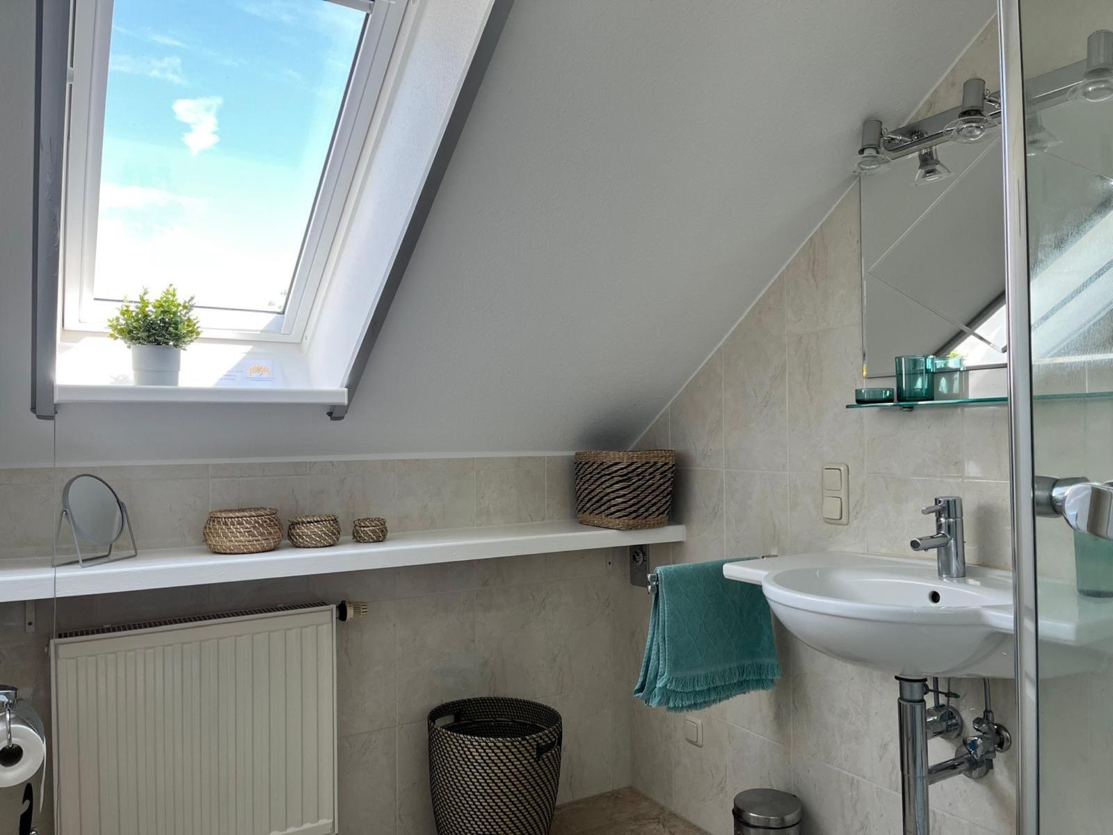 Badezimmer mit Dachschrägen, Waschbecken, Dusche und Fenster.