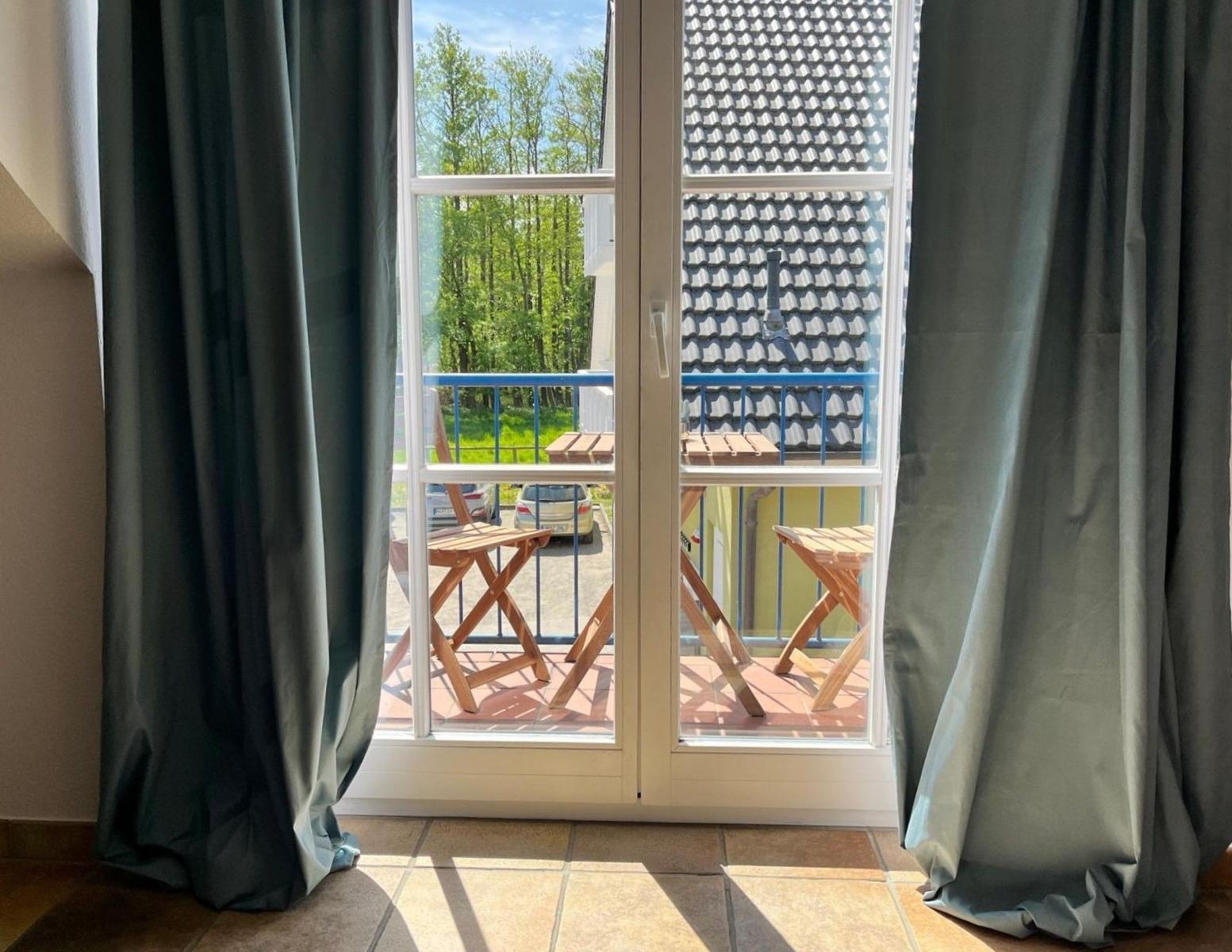 Durch die Glastüren ist ein Balkon mit Holztischen und Stühlen zu sehen.