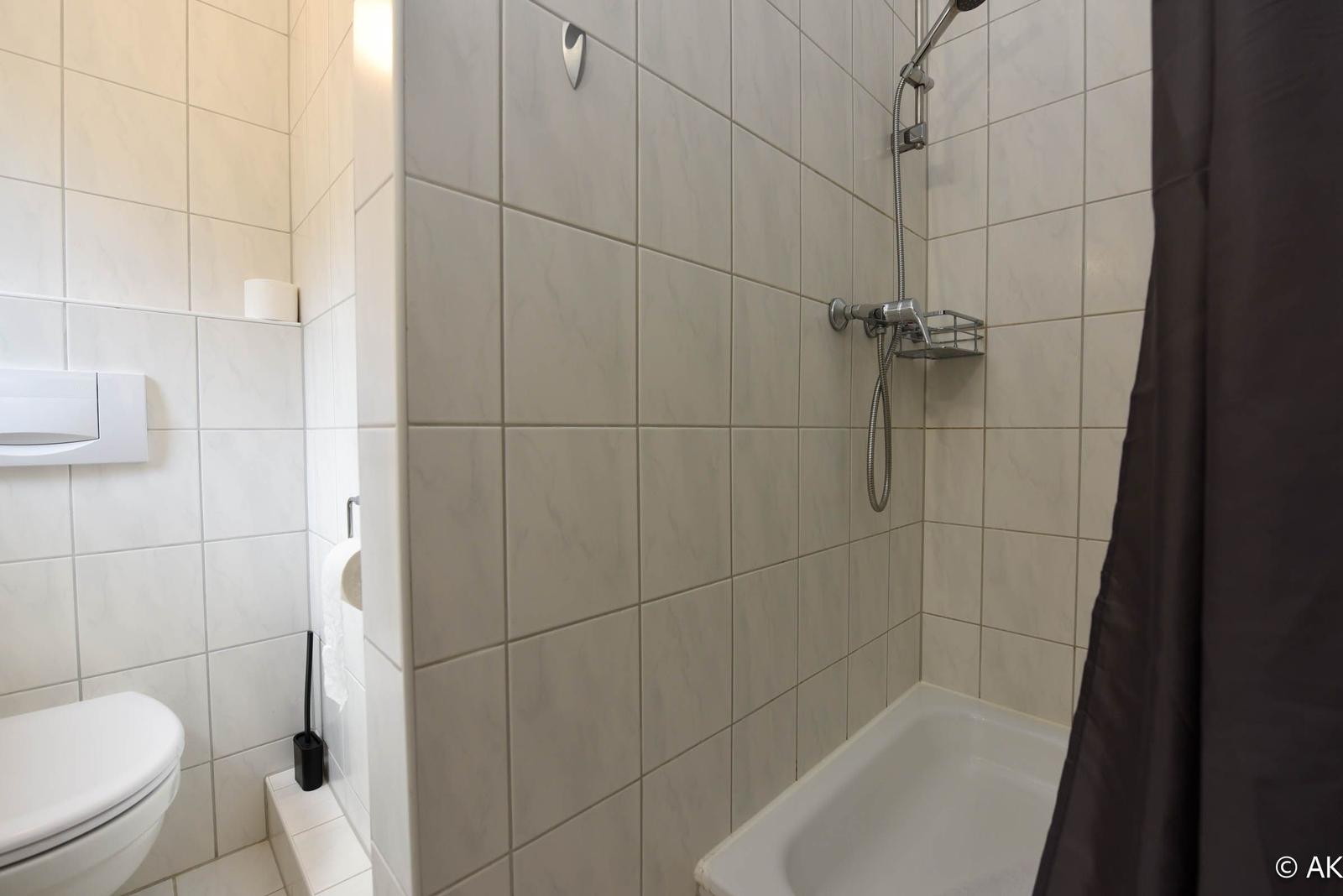 Badezimmer mit Dusche, Toilette und Duschvorhang.