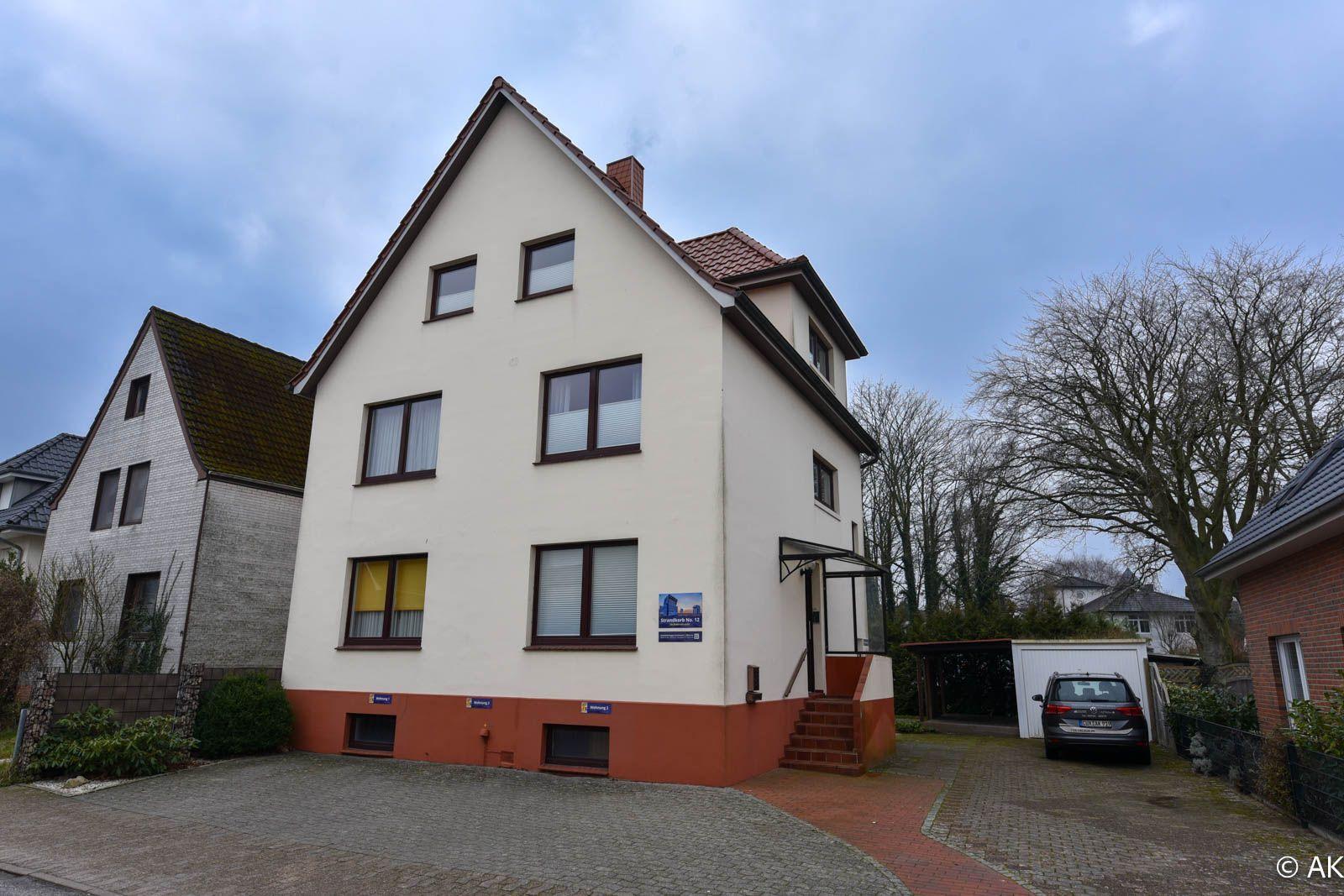 Drei-stöckiges Haus mit Terrasse und Garage. Vorhof mit gepflastertem Weg.