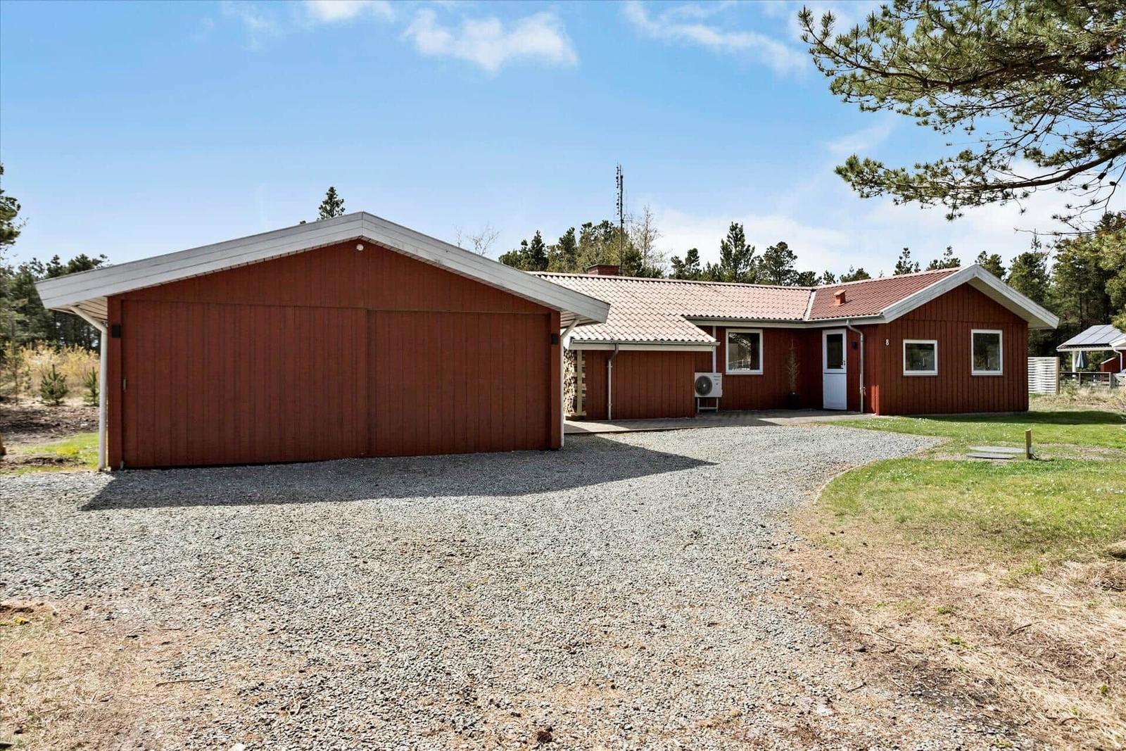 Rotes Holzhaus mit Garage und Kiesweg im Wald