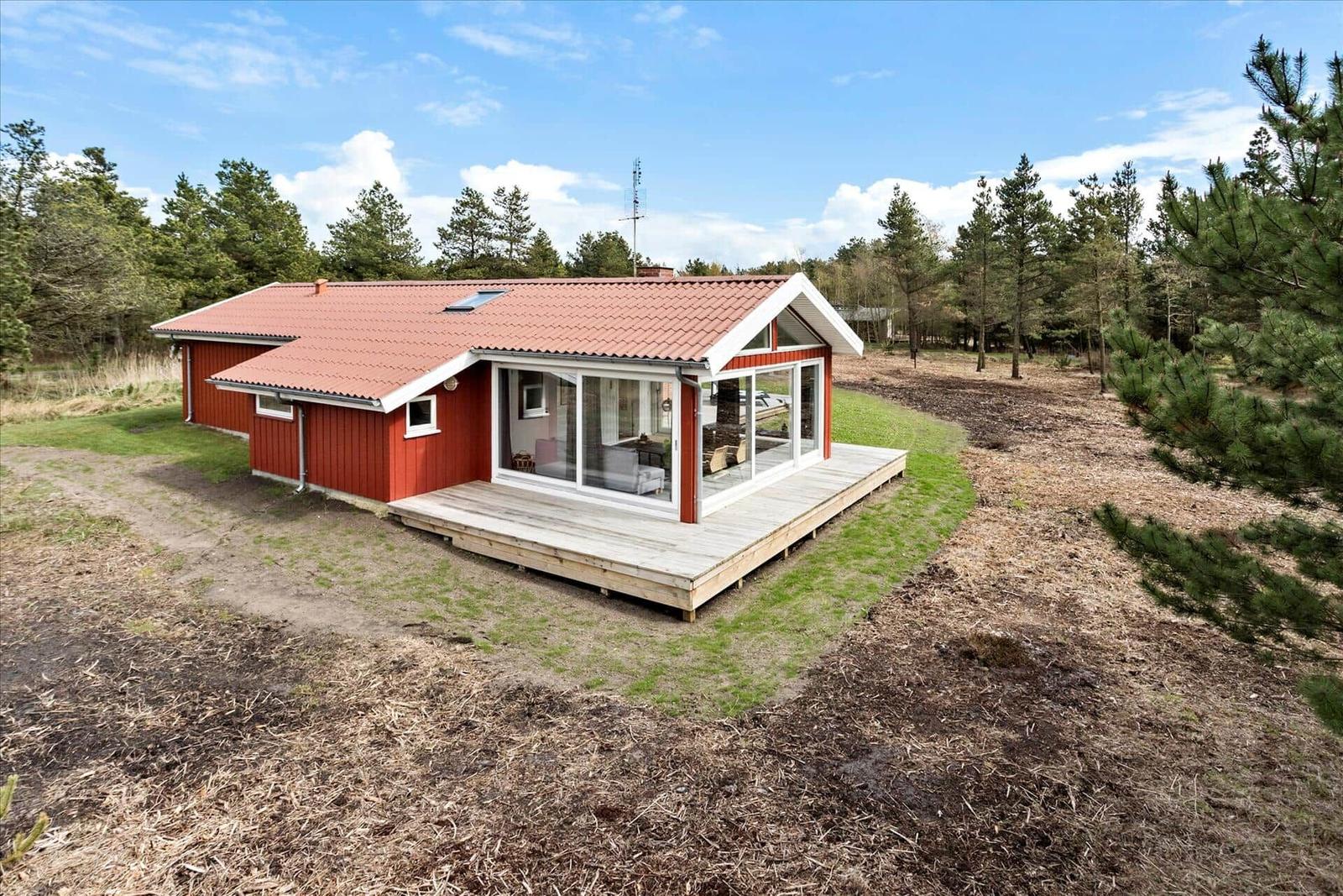 Rotes Haus mit Terrasse und Glasfront im Wald