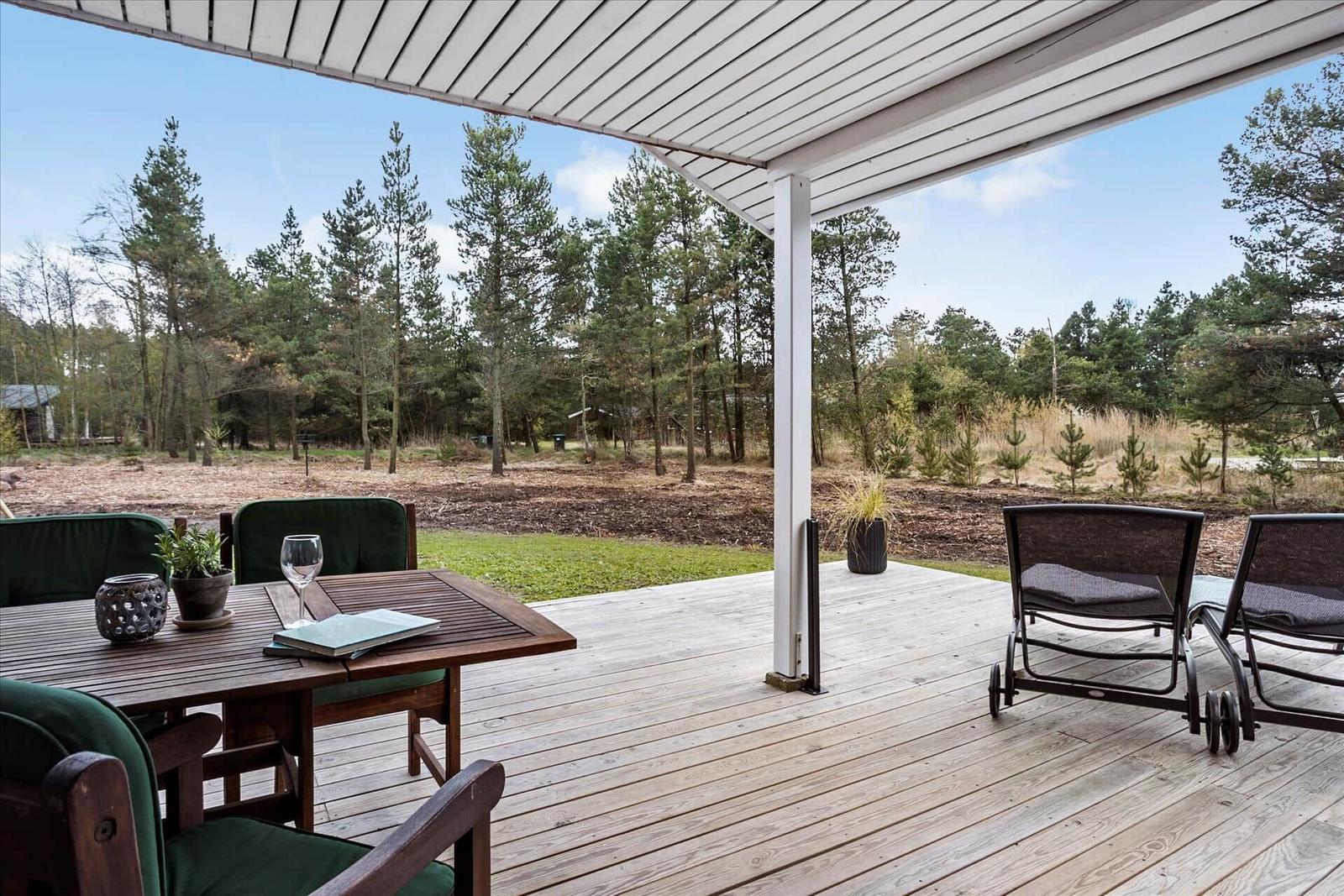 Terrasse mit Tisch, Stühlen und Blick in den Wald.