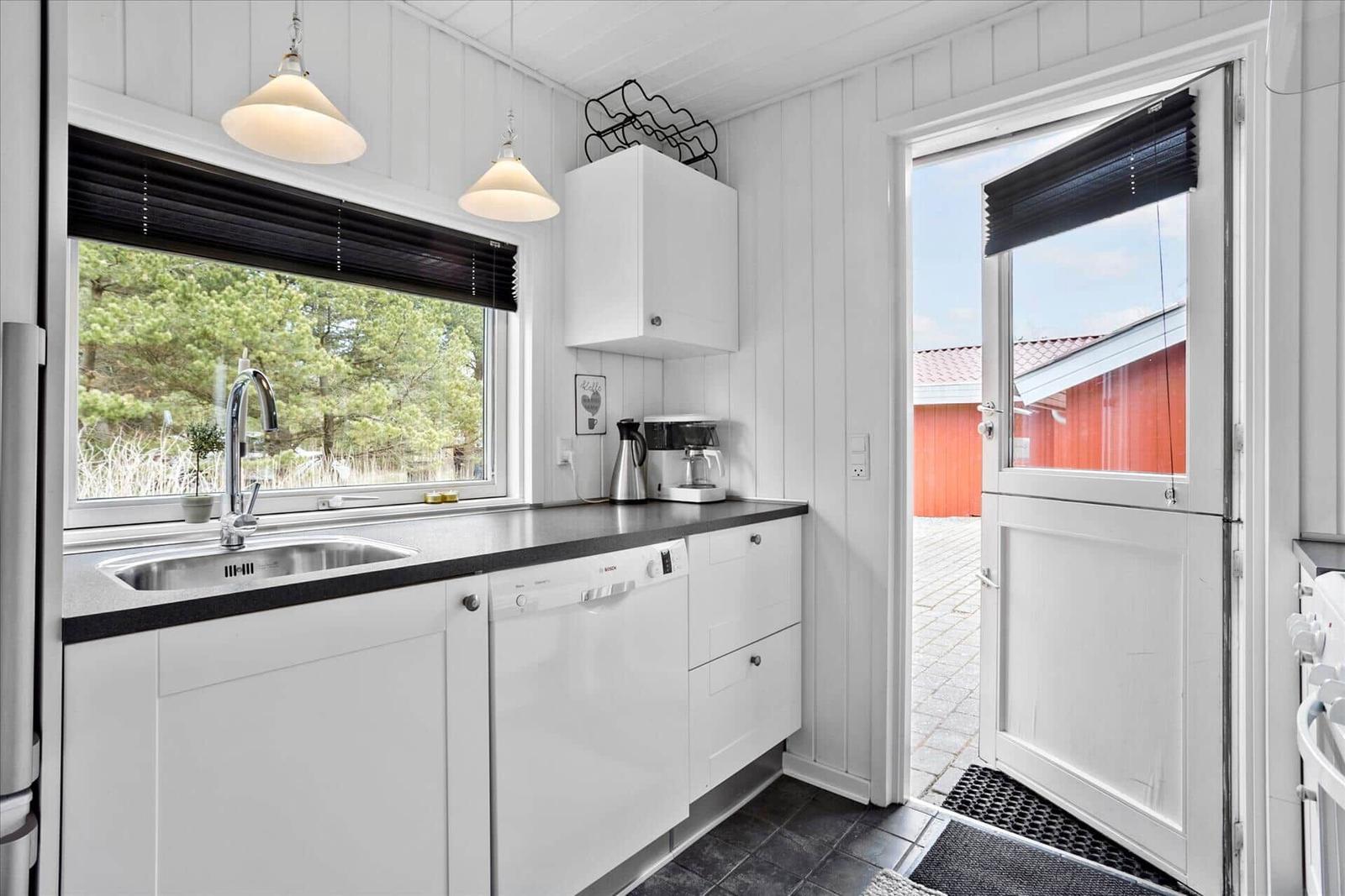Küche mit Waschmaschine, Fenster und Tür zum Hof.