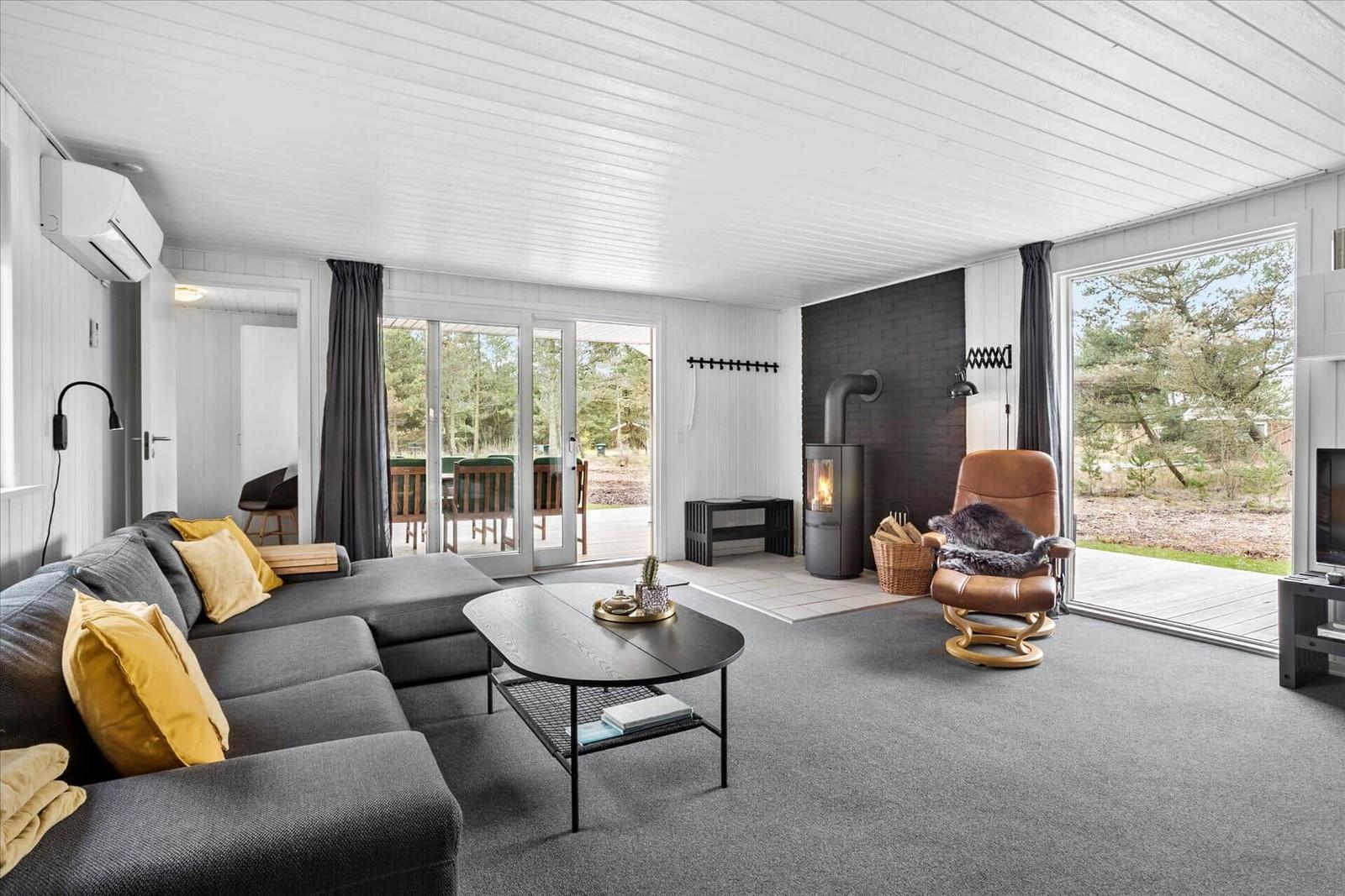 Wohnzimmer mit Sofa, Kamin und Terrasse