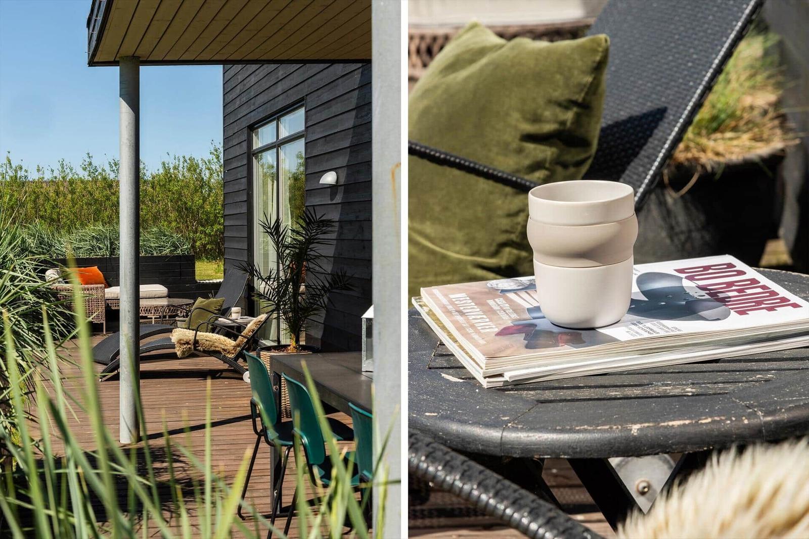 Terrasse mit Sitzgelegenheiten und Tisch. Auf dem Tisch steht eine Tasse und Zeitschriften.