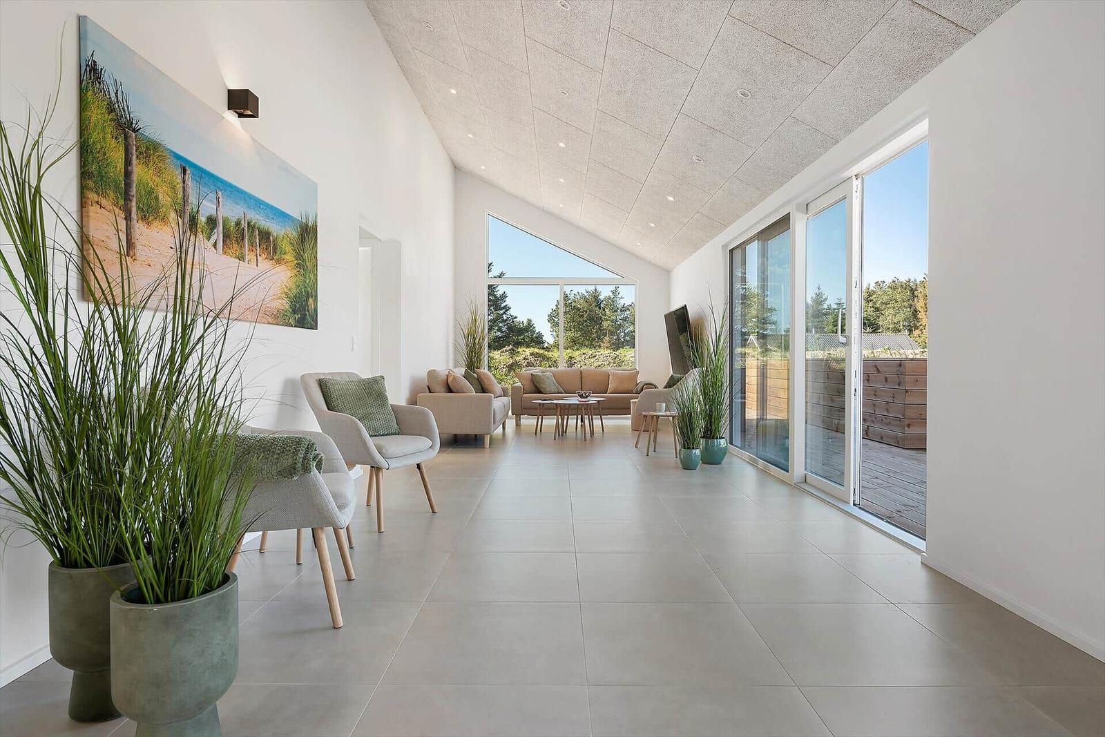 Spacious room with seating and large windows. Outdoor terrace with wooden railing.