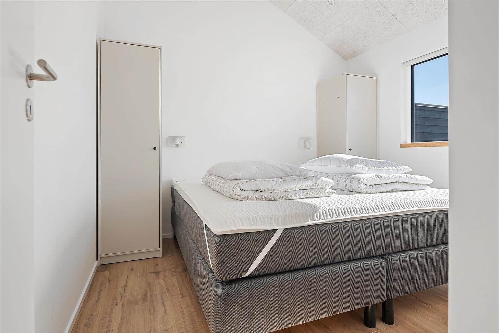 Bedroom with bed, wardrobes, and window.