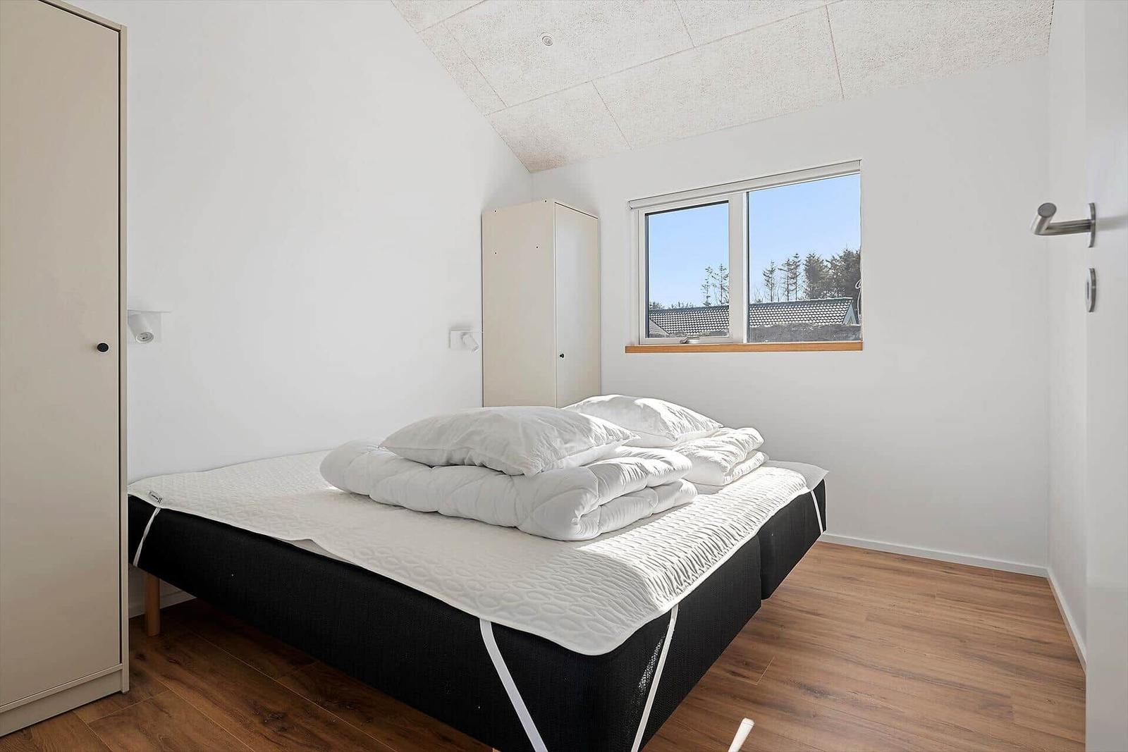 Bedroom with bed, wardrobe, and window overlooking outdoor area.