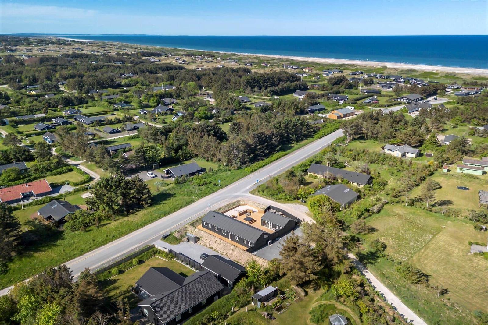 Aerial view of holiday homes near the beach with green lawns and trees.