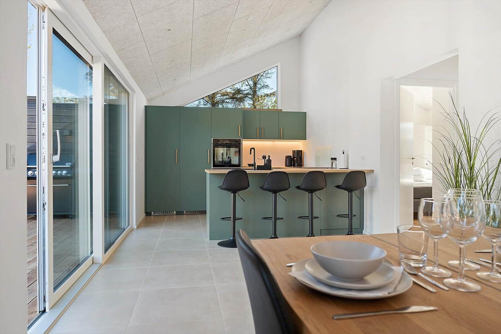 Kitchen with green cabinets and dining table with dishes