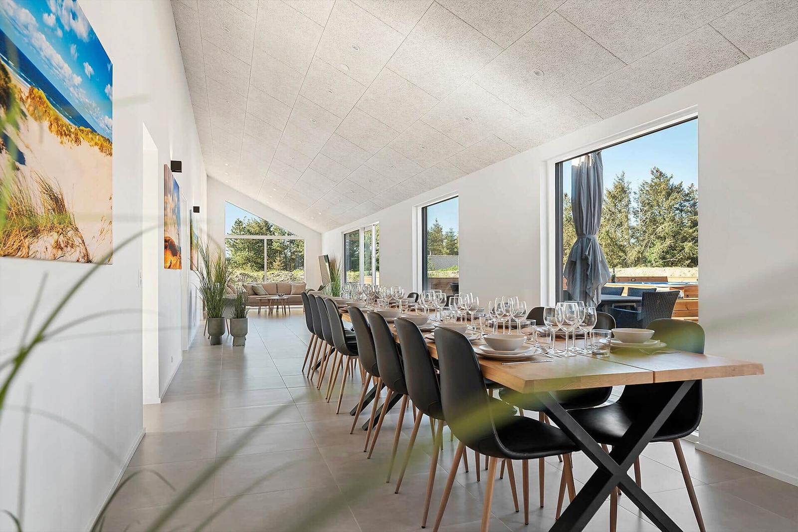 Long dining room with table and chairs, large windows and wall art