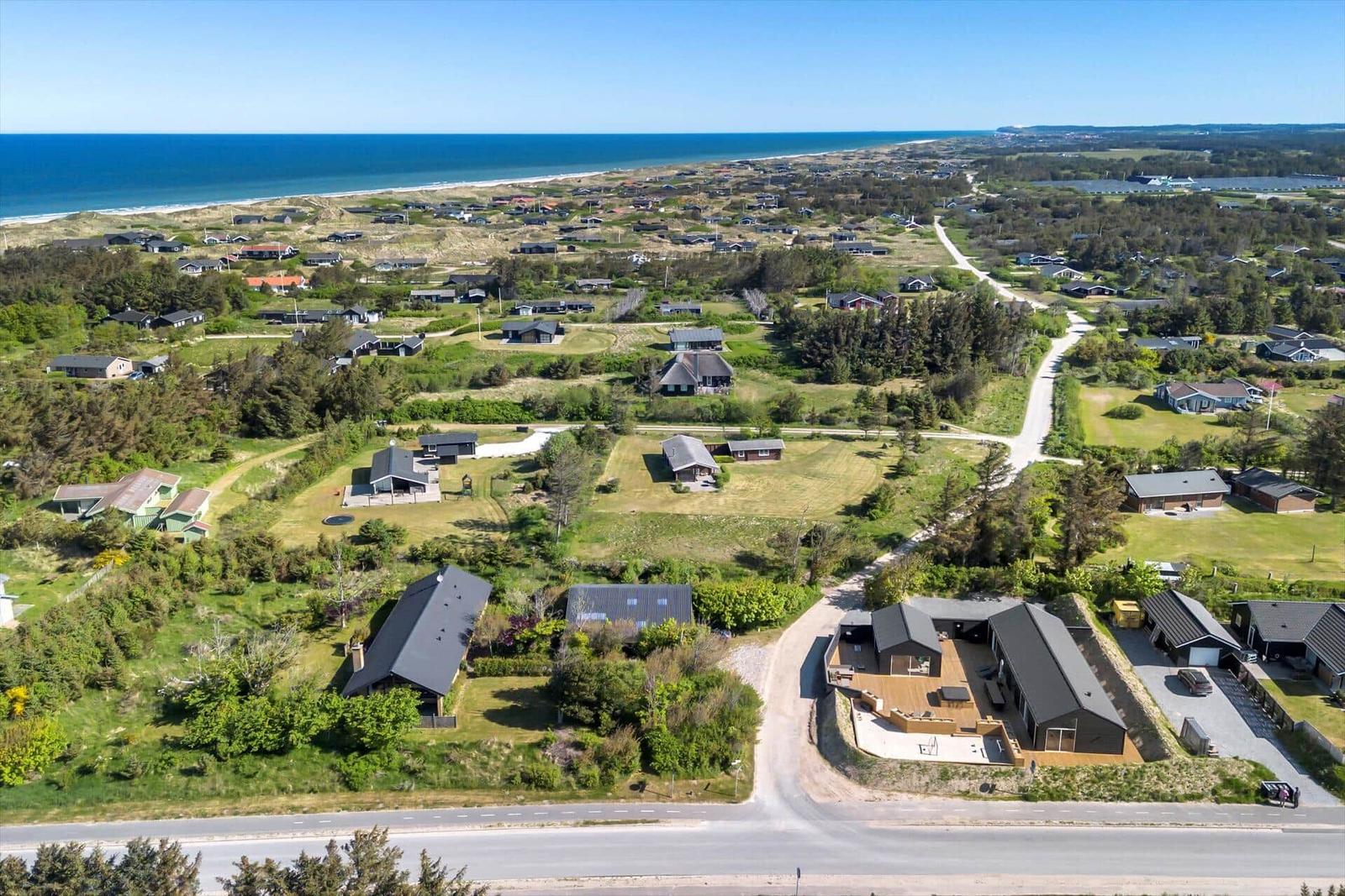 Aerial view of coastal holiday homes with green lawns and ocean in background.