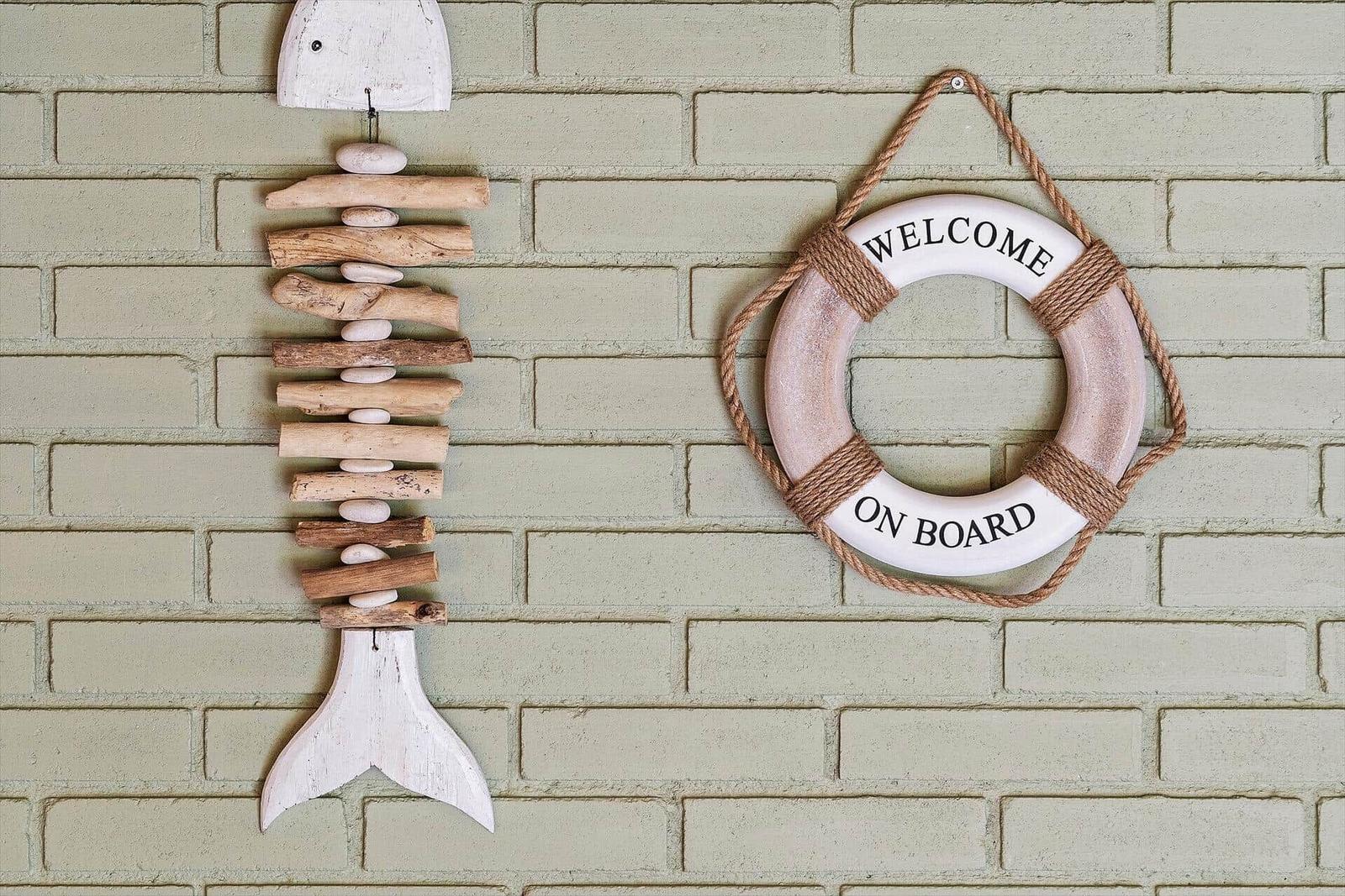 Wanddekoration mit Fisch aus Holz und Rettungsring mit Aufschrift.