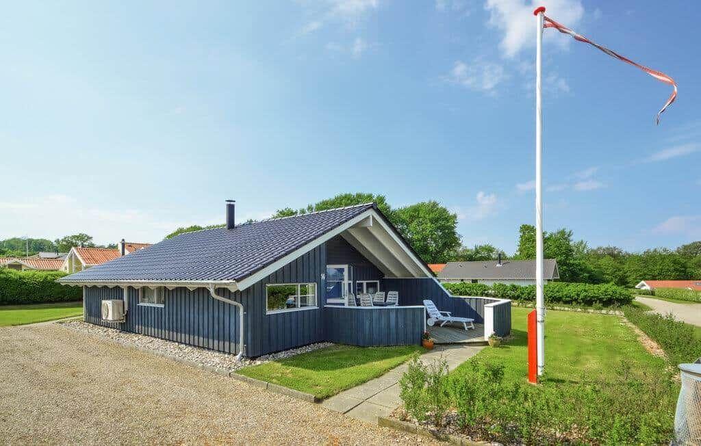 A blue holiday home with terrace and garden under a blue sky.