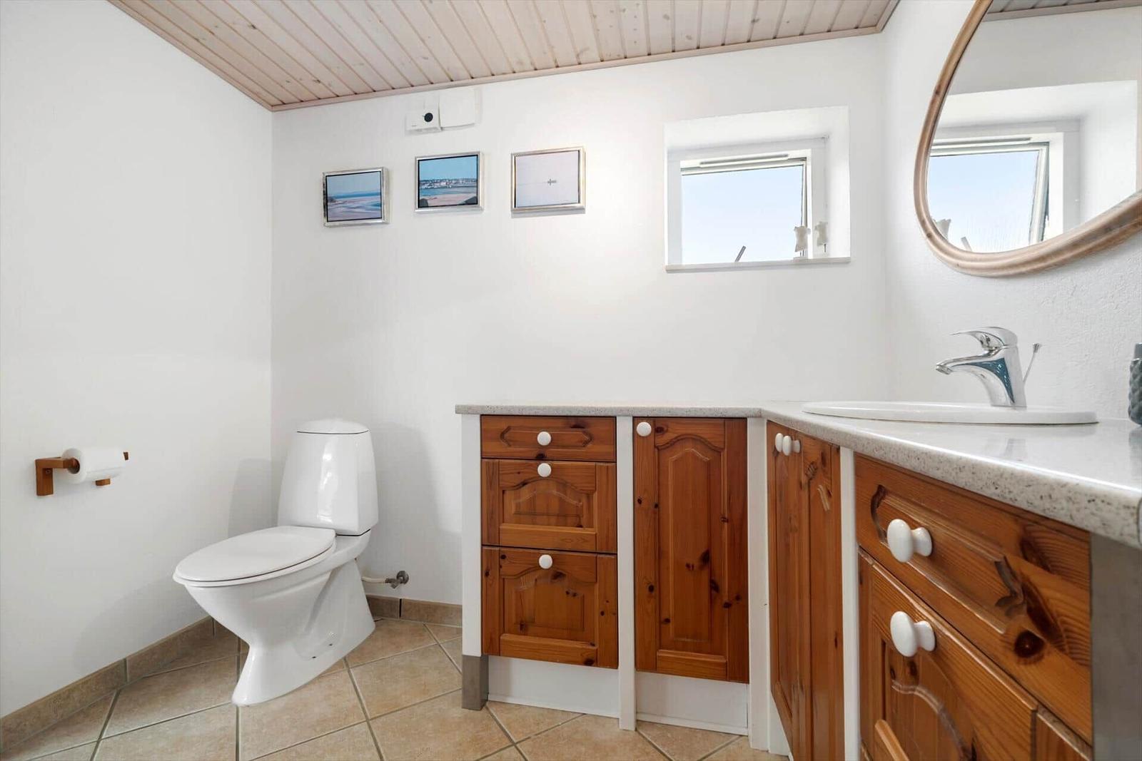 Badezimmer mit Holzschrank, Waschbecken und Toilette