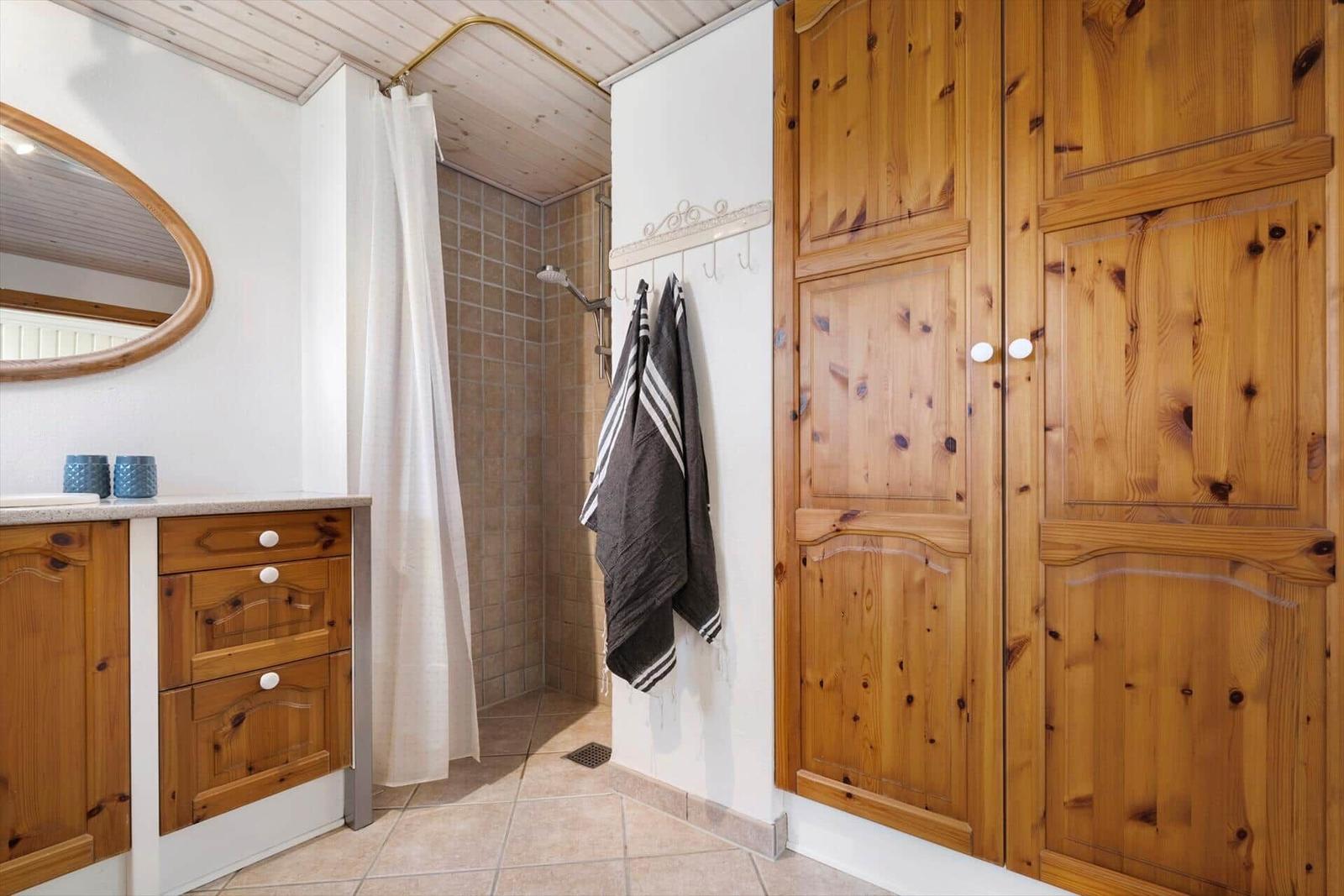 Badezimmer mit Dusche, Holzschränken und Waschbecken