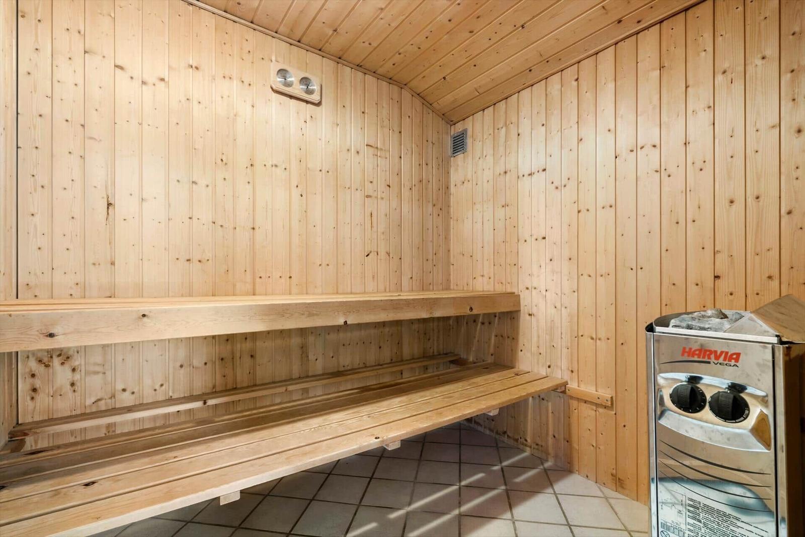 Sauna mit Holzwand und Sitzbank, Heizgerät rechts