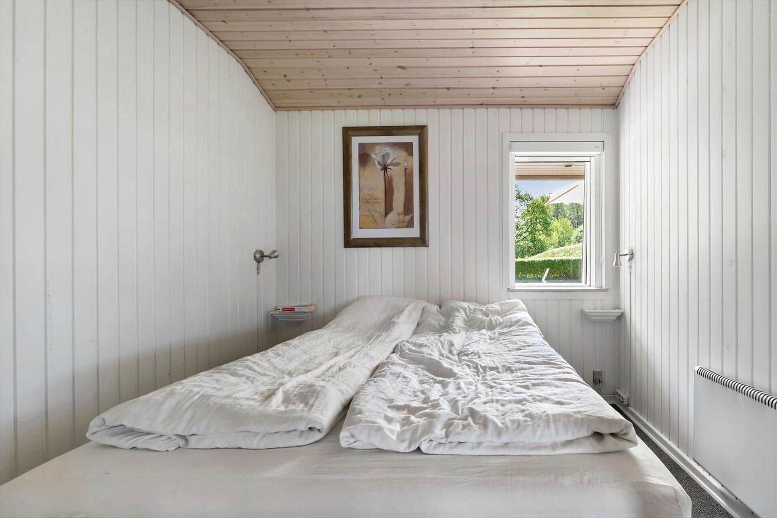 Schlafzimmer mit Bett, Fenster und Wandbild.
