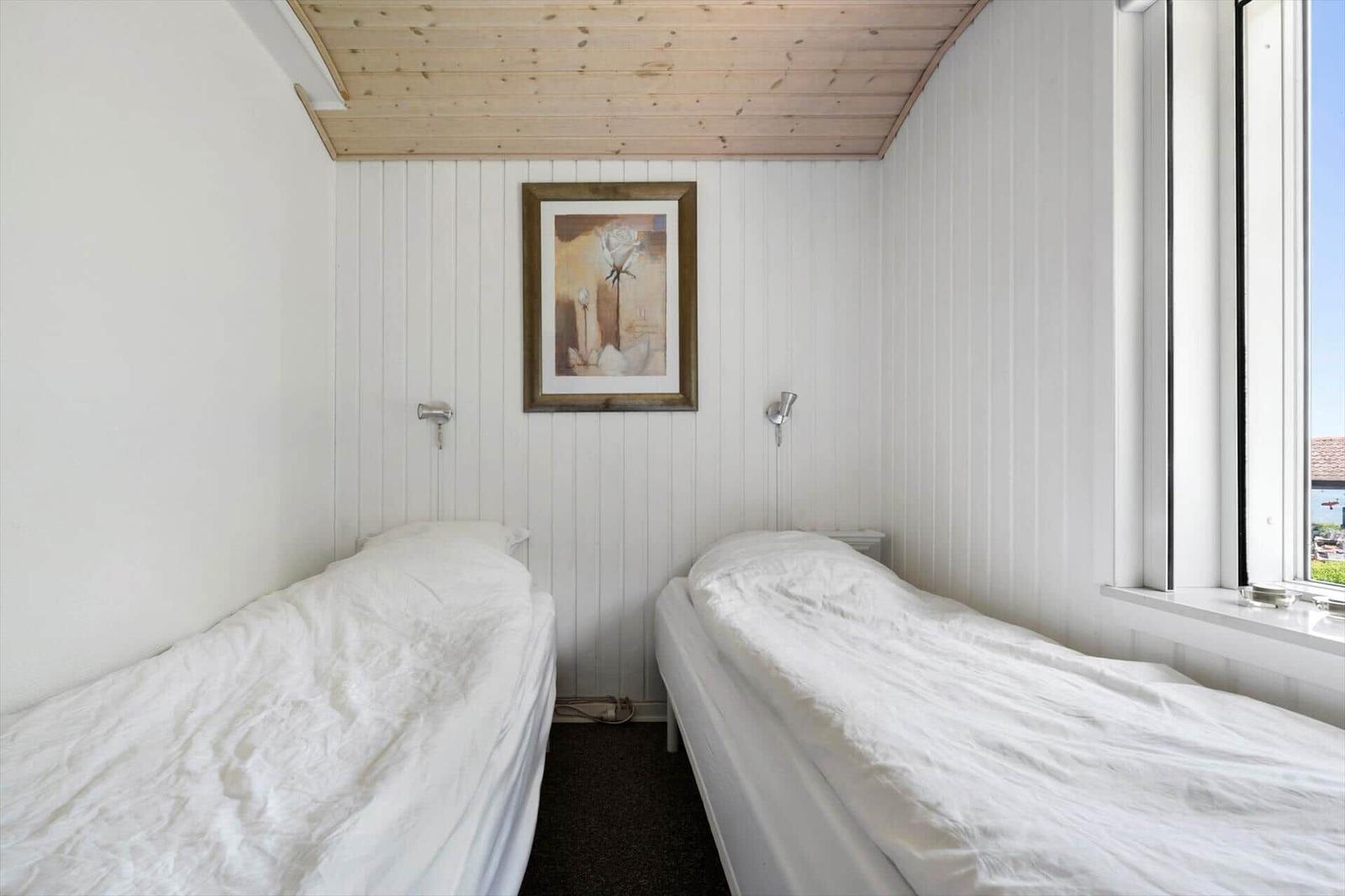 Zwei Betten mit weißen Bettwäschen, Wandbild und Fenster mit Blick.