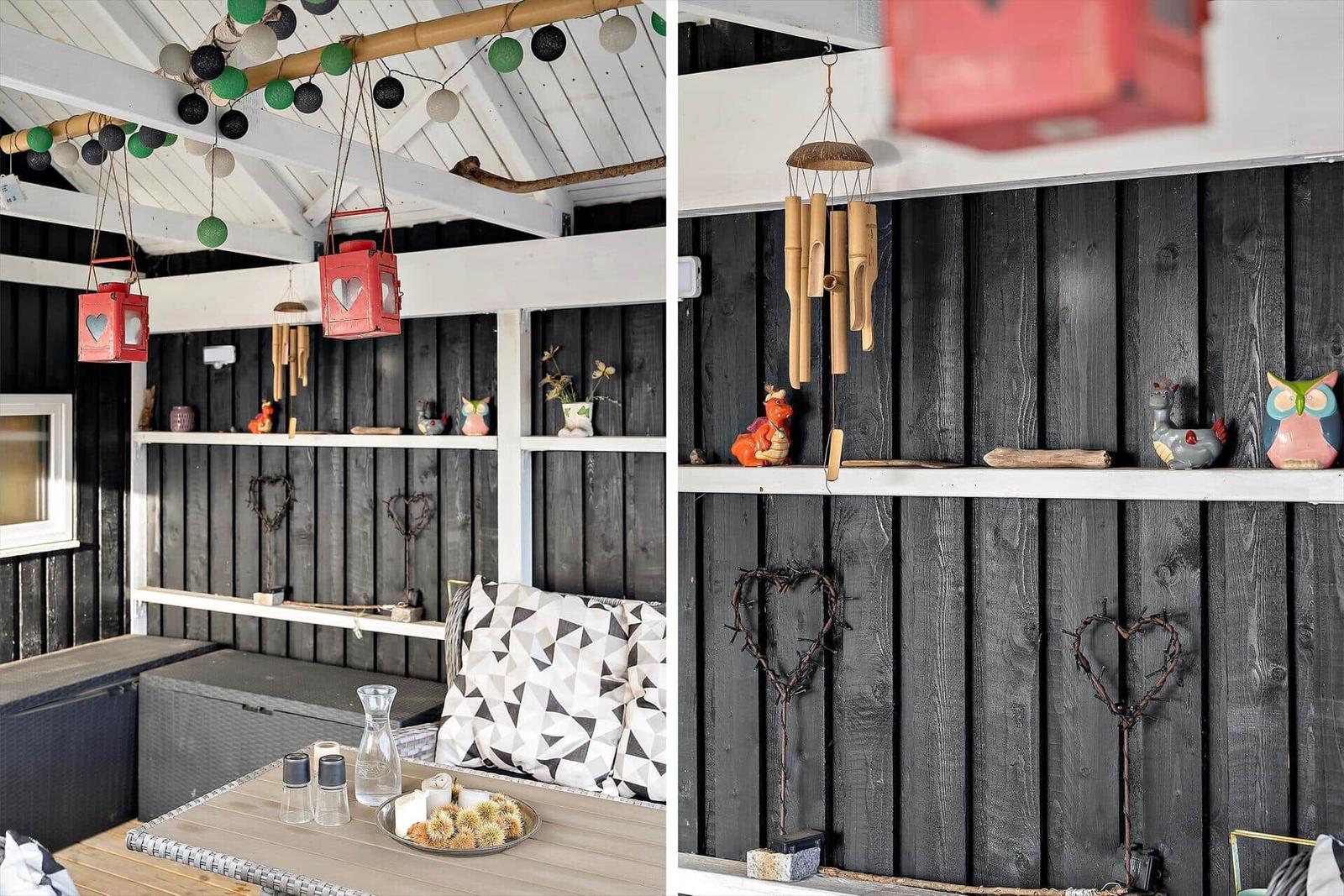 Deck with table, chairs, and decor on black wooden walls.